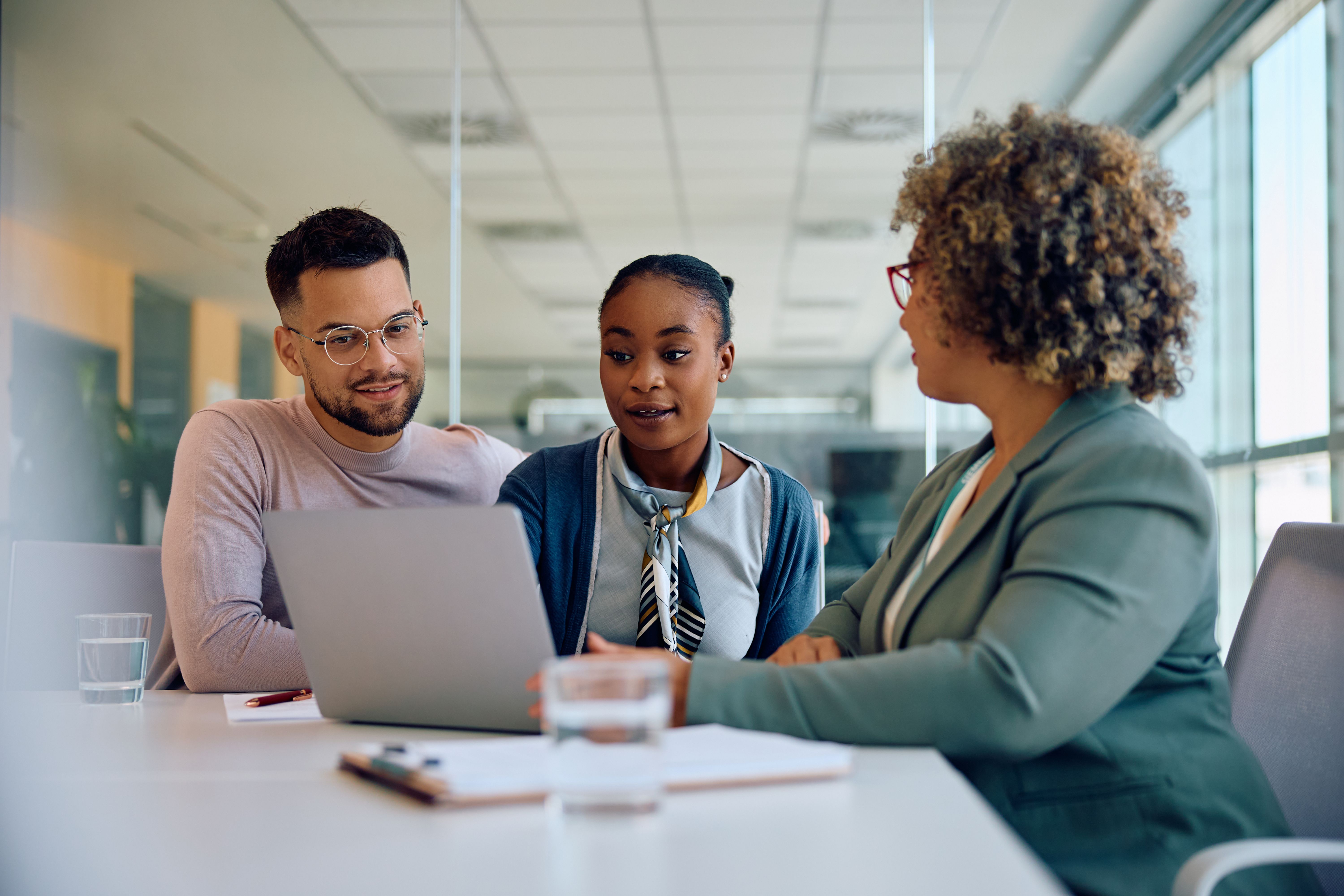 Young couple and their financial advisor using laptop during a meeting in the office.