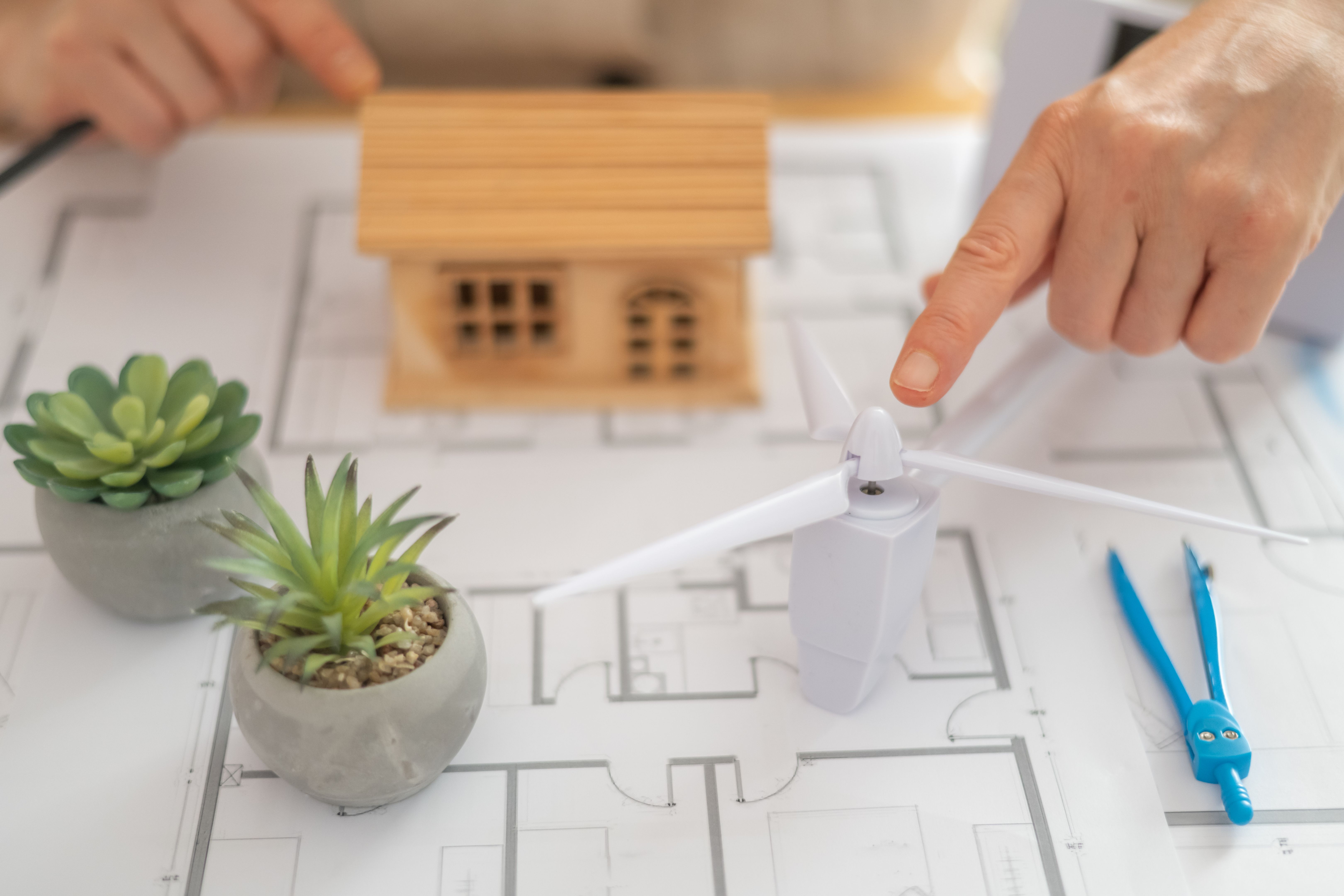 Architect designing a sustainable house powered by a wind turbine, emphasizing renewable energy and an ecological future while creating innovative solutions for green living