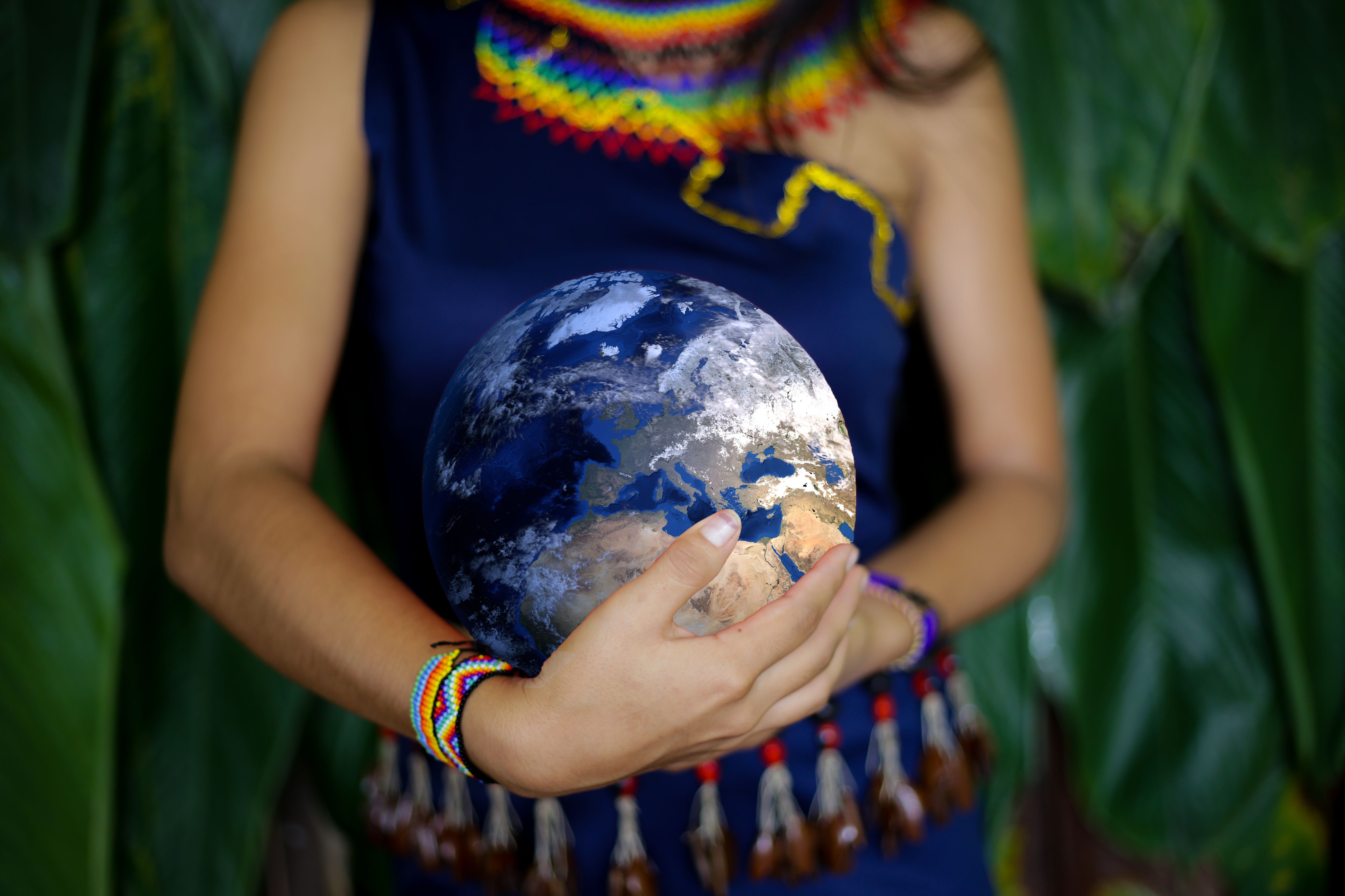 An indigenous female in traditional clothing holding the earth with two hands close to her belly An indigenous female in traditional clothing holding the earth with two hands close to her belly