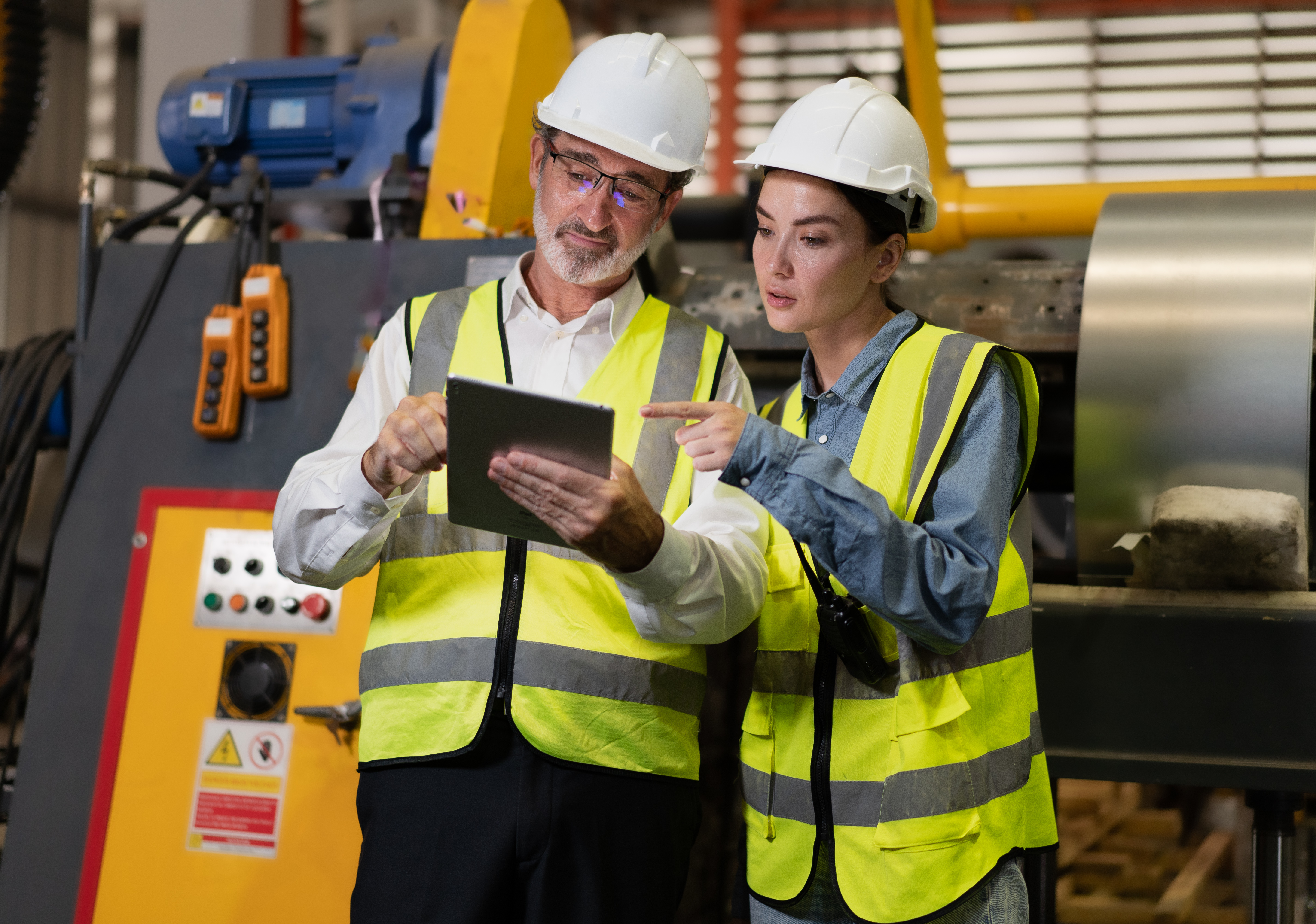 Senior manager on job training female technician working in metal sheet production factory. Senior manager on job training female technician working in metal sheet production factory.