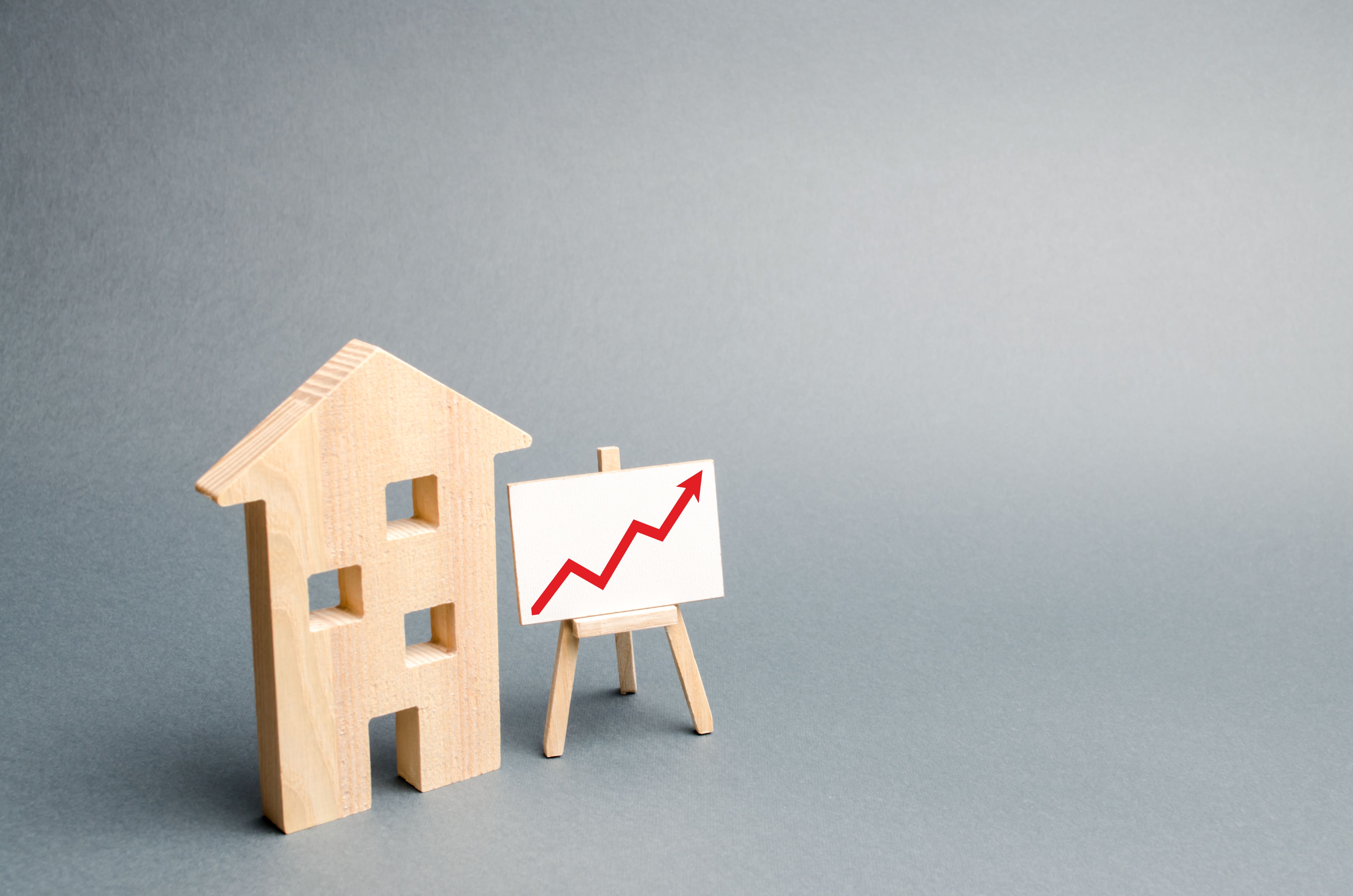 Casa de madera y soporte con flecha roja hacia arriba. Creciente demanda de vivienda inmobiliaria. crecimiento de la ciudad y su población. Inversiones. alza de los precios de vivienda o alquiler. Costos crecientes. El enfoque selectivo