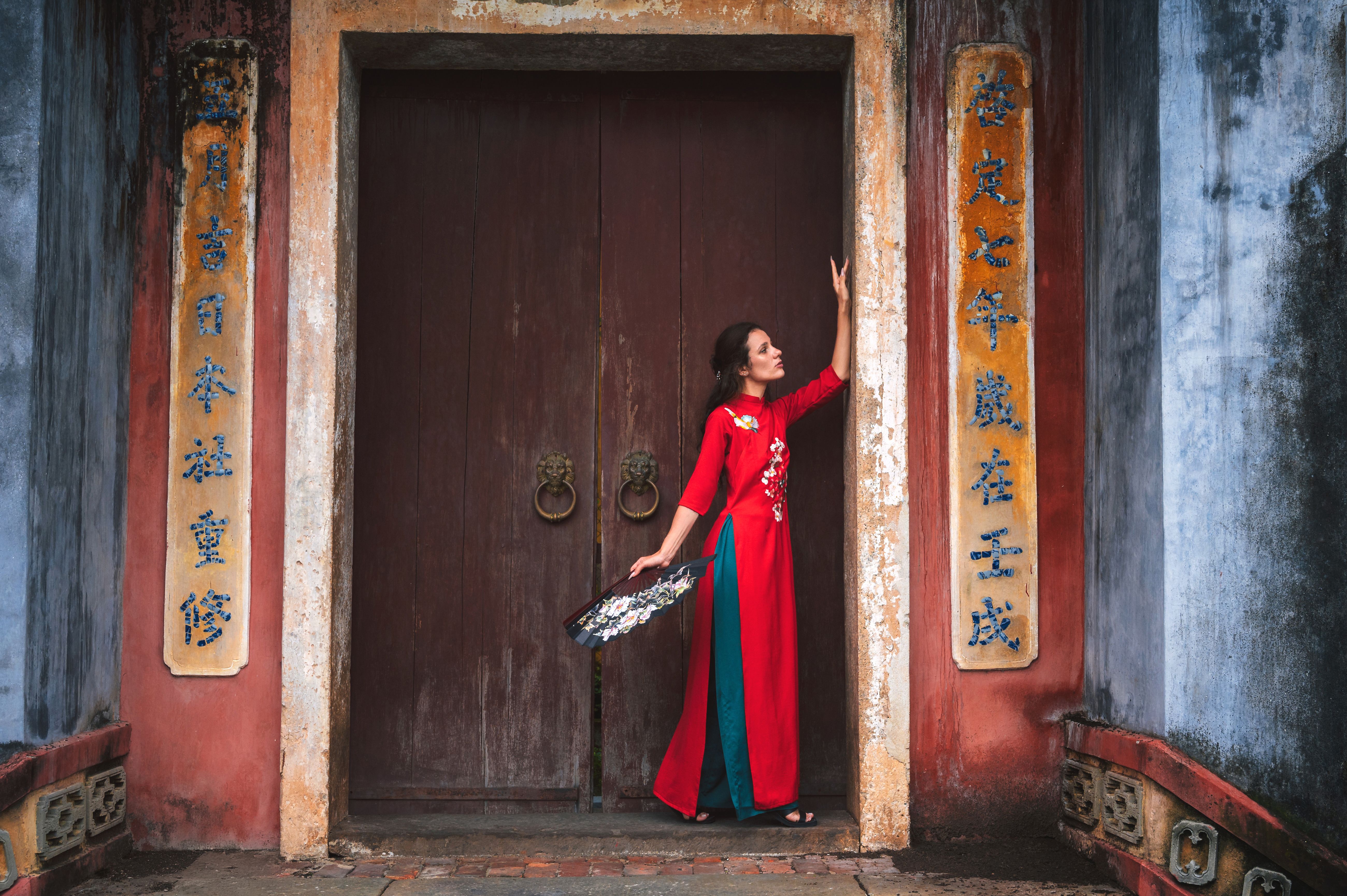 female traveler visiting asia. tourist in hat and traditional vietnamese dress visiting oriental buddhist temple in Hoi an