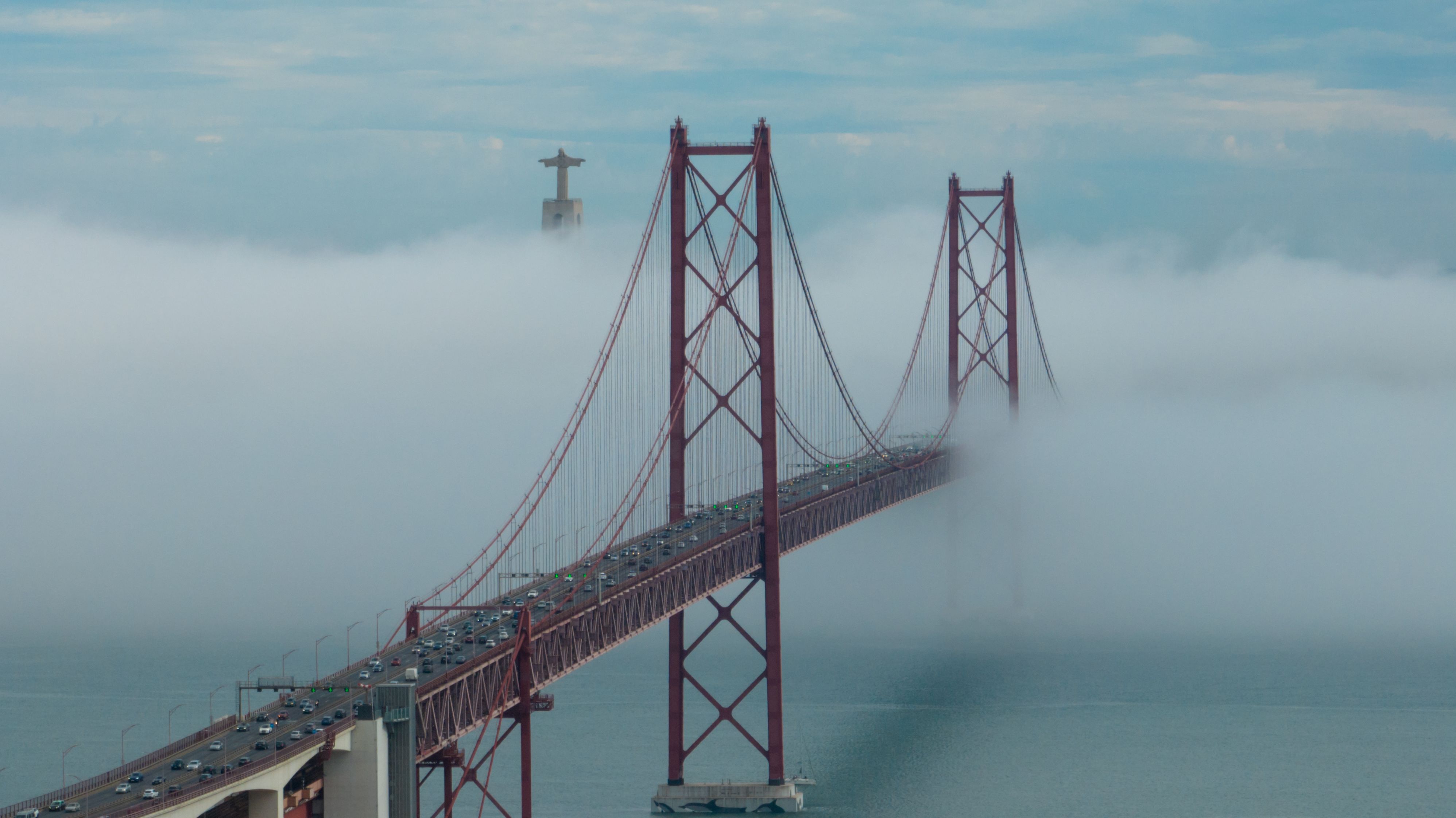 Vista aérea 25 de Abril Ponte, Lisboa, coberta de neblina com vários transportes de um lado para o outro