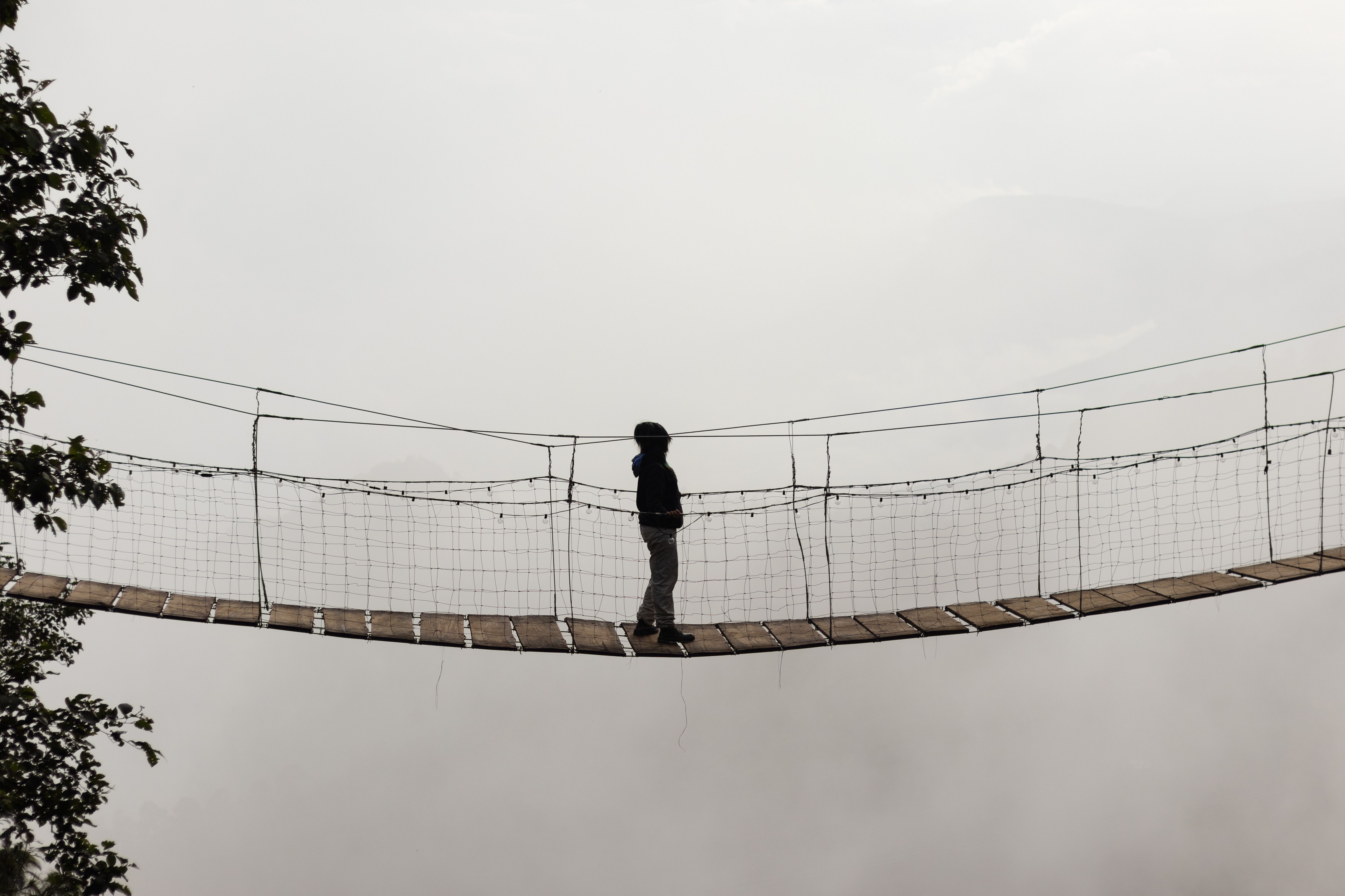 Silhouette of a woman crossing a bridge contemplating the landscape of clouds and fog on her vacation alone