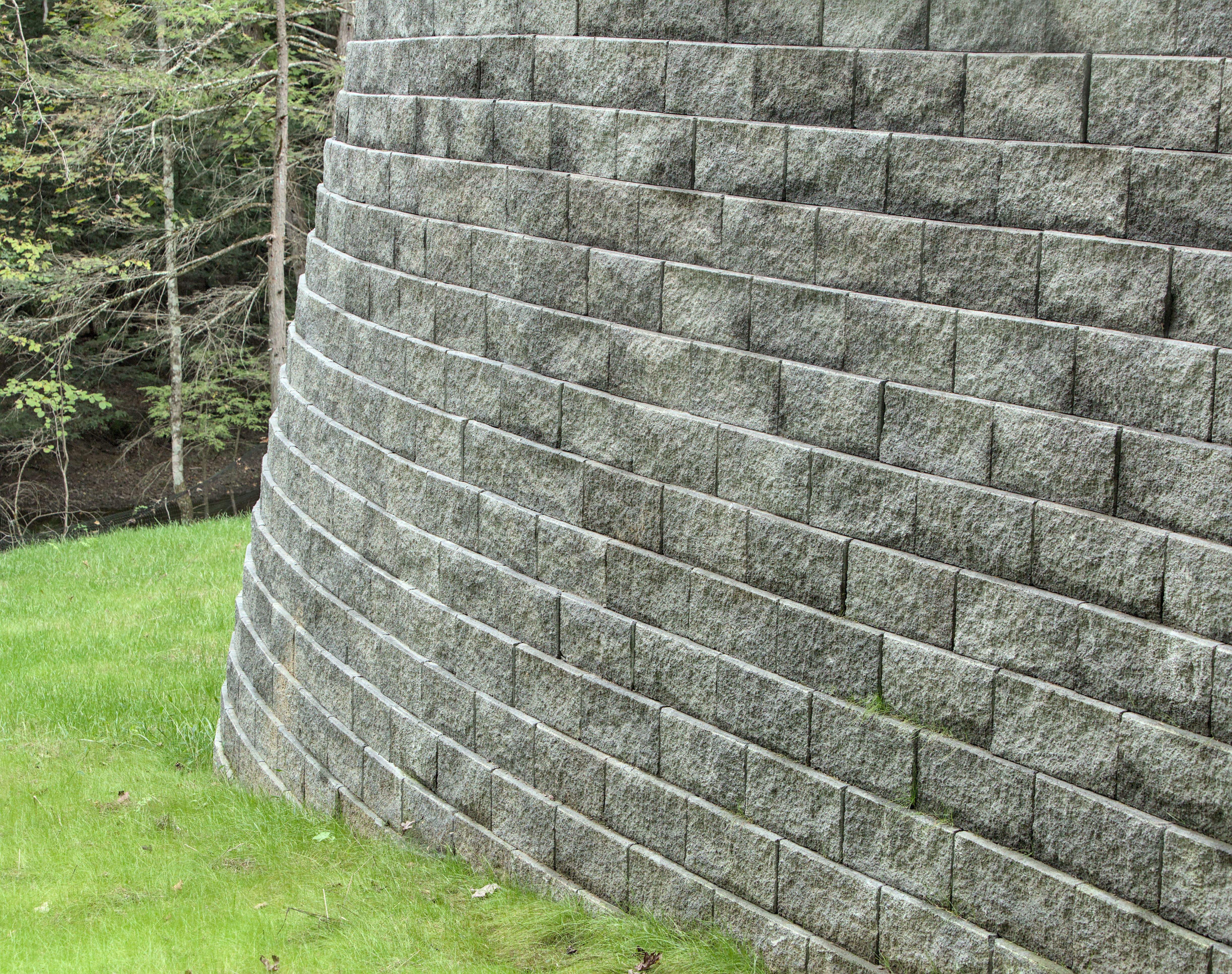 tall stone retaining wall (curved brick masonry) in house back yard (large gray supporting structure) tall stone retaining wall (curved brick masonry) in house back yard (large gray supporting structure)