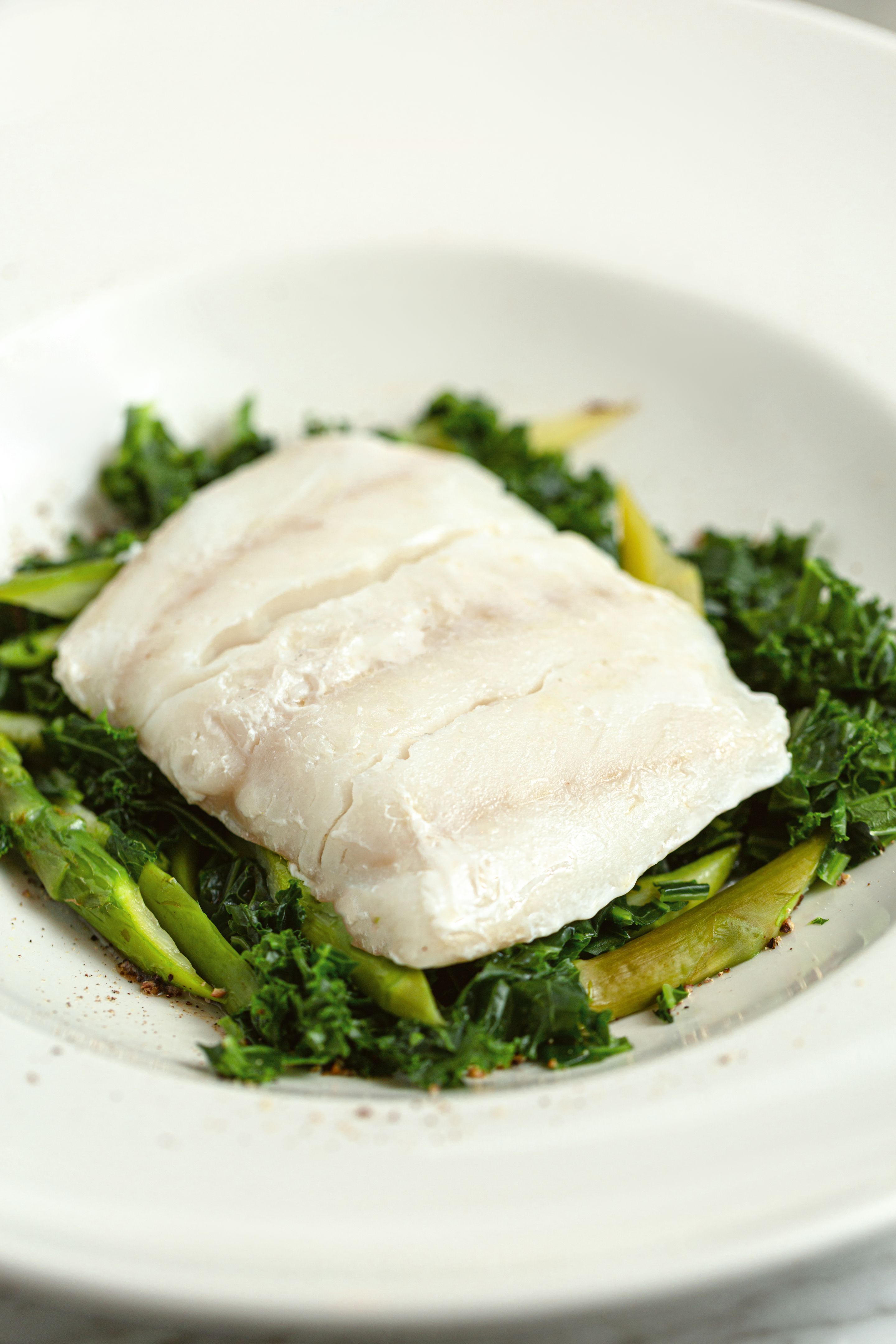 Fried cod fillet with fresh green vegetables. Close up.