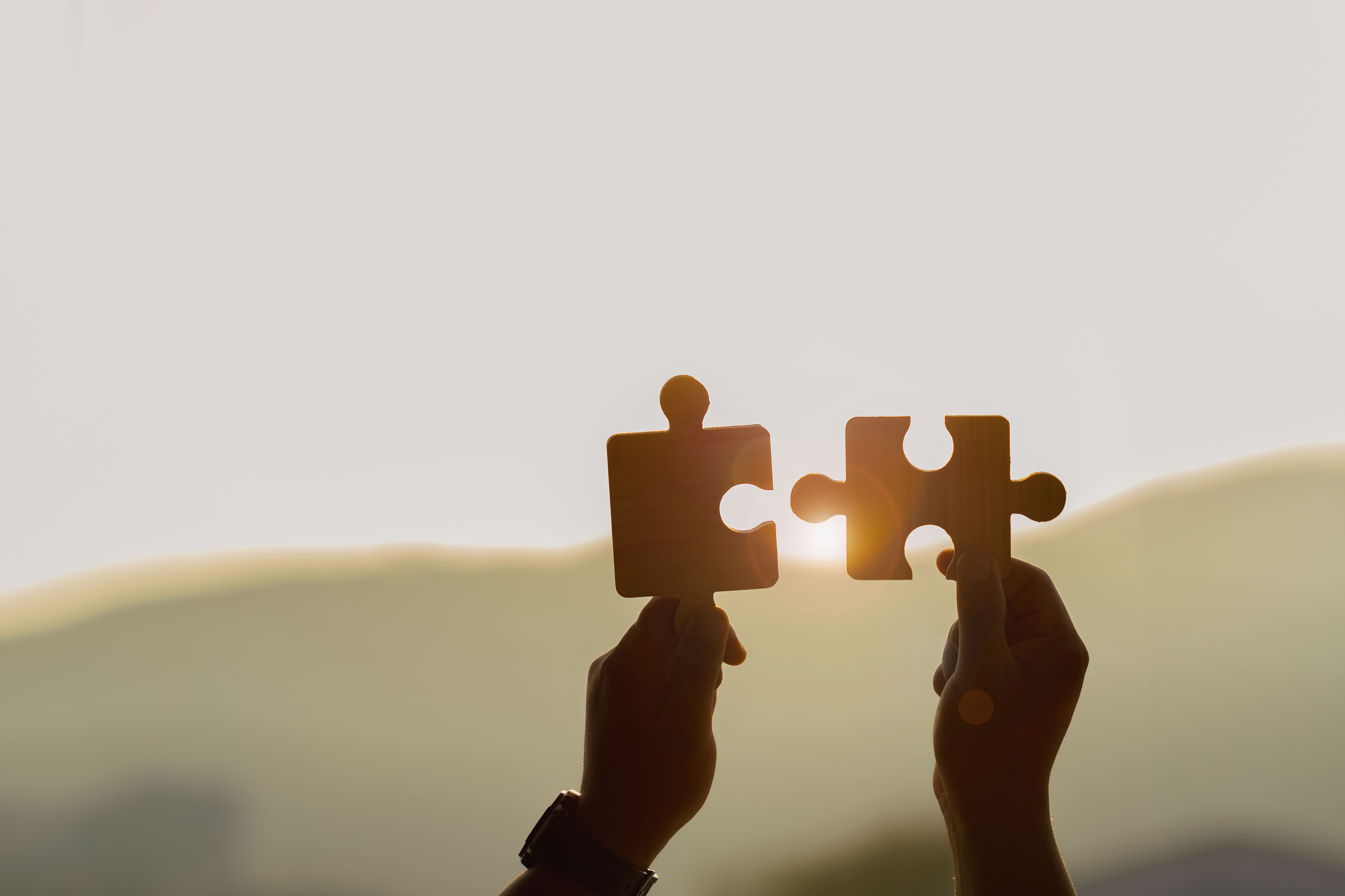 Silhouette Two hands of businessmen connecting a couple of puzzle pieces against the sunrise effect, partnership.Charity, Teamwork.
Business solutions, targets, success, goals, and strategy concepts.