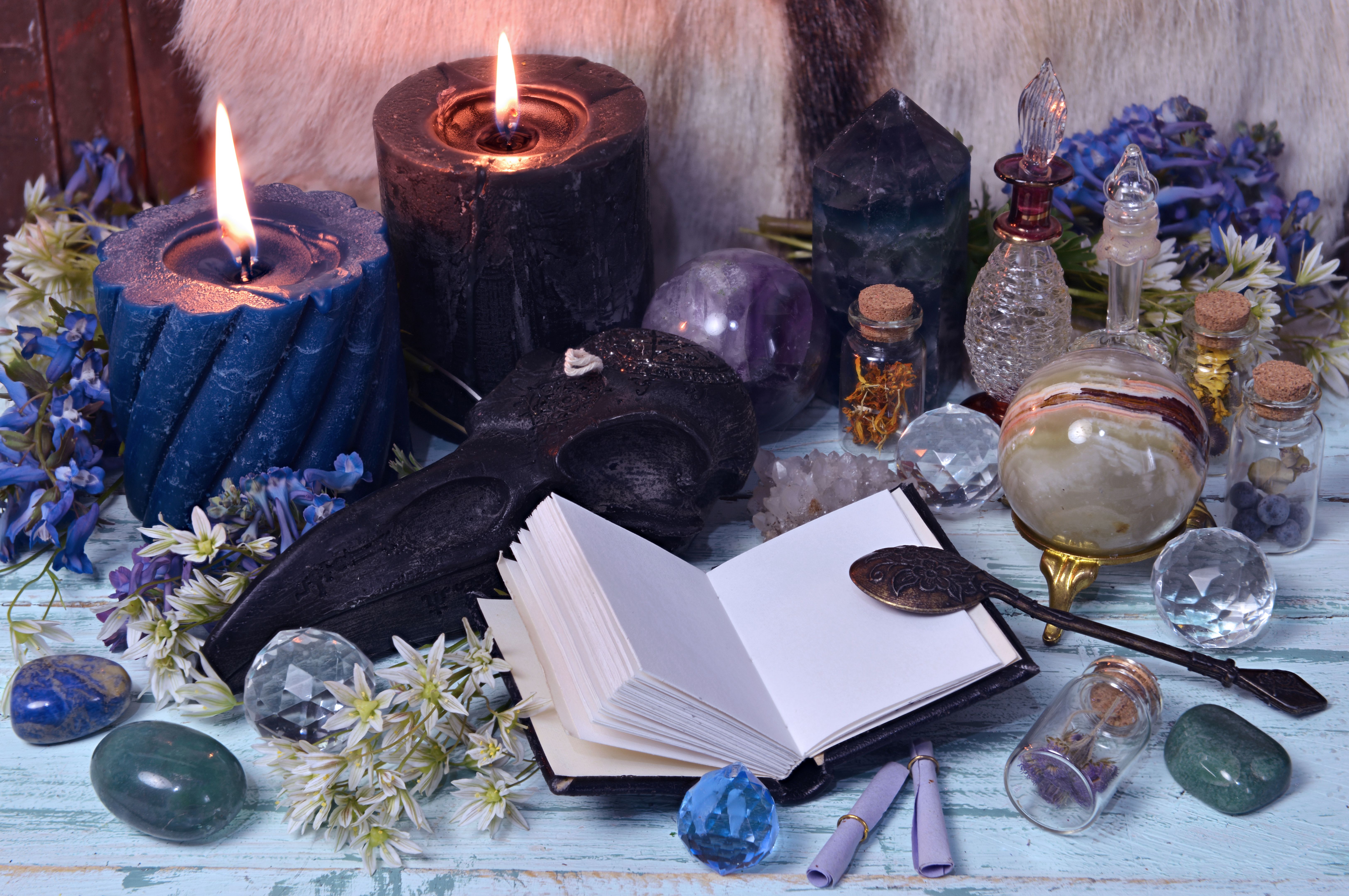 Still life with open diary book, crystals, flowers and burning candles.