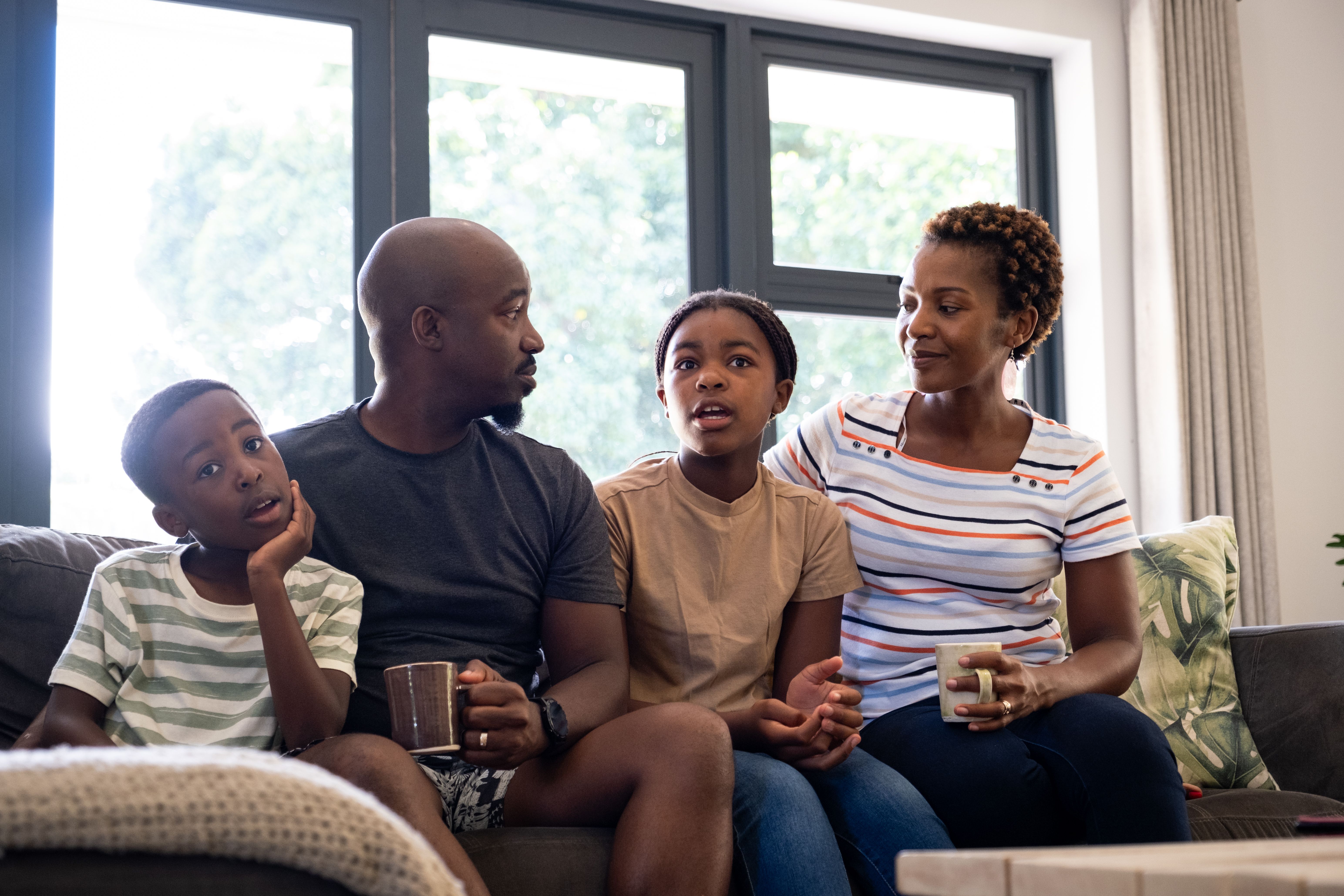 Black family enjoy sitting on the sofa watching a movie together