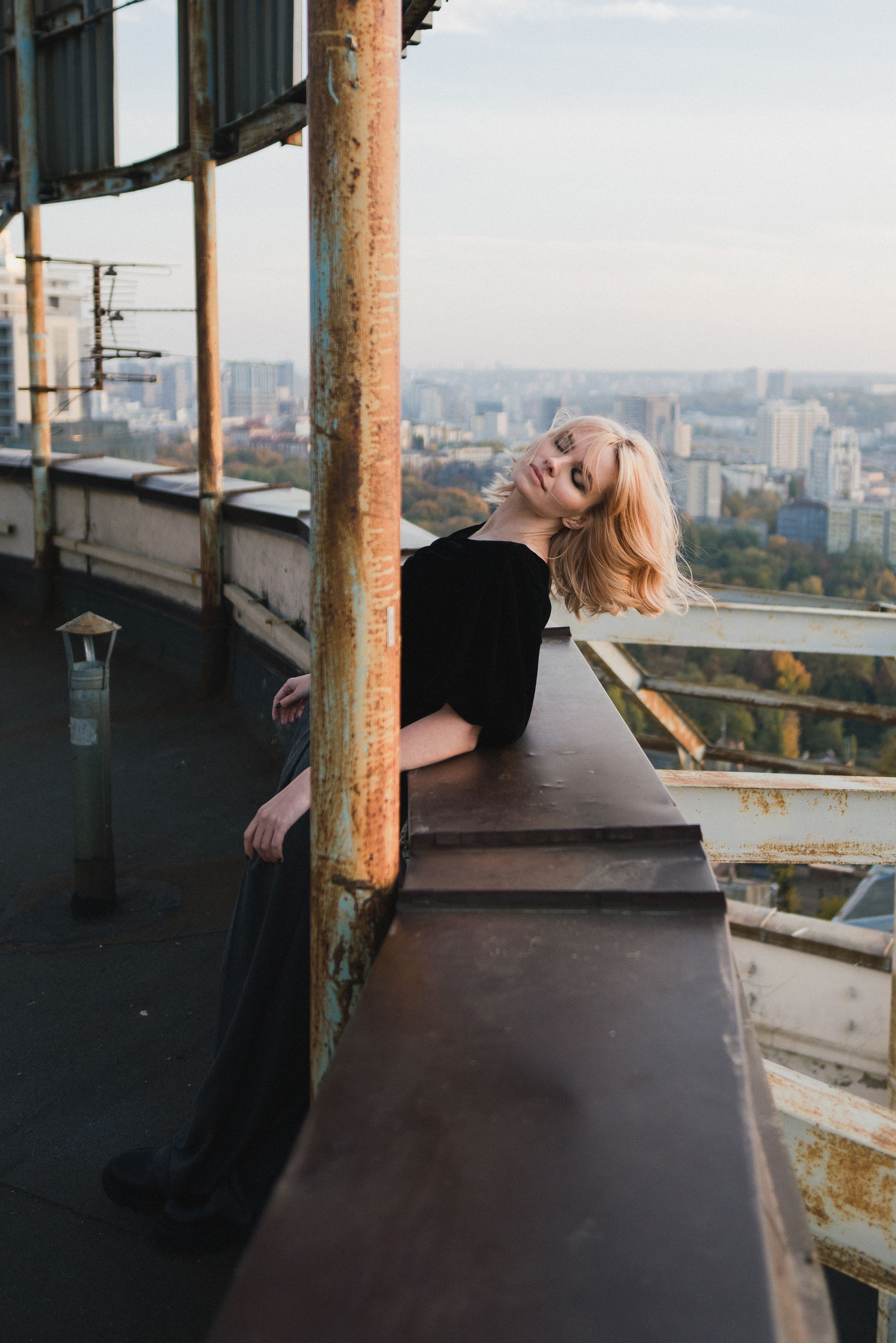 Romantic and beautiful caucasian woman in stylish clothes on the rooftop enjoying herself and the city view.