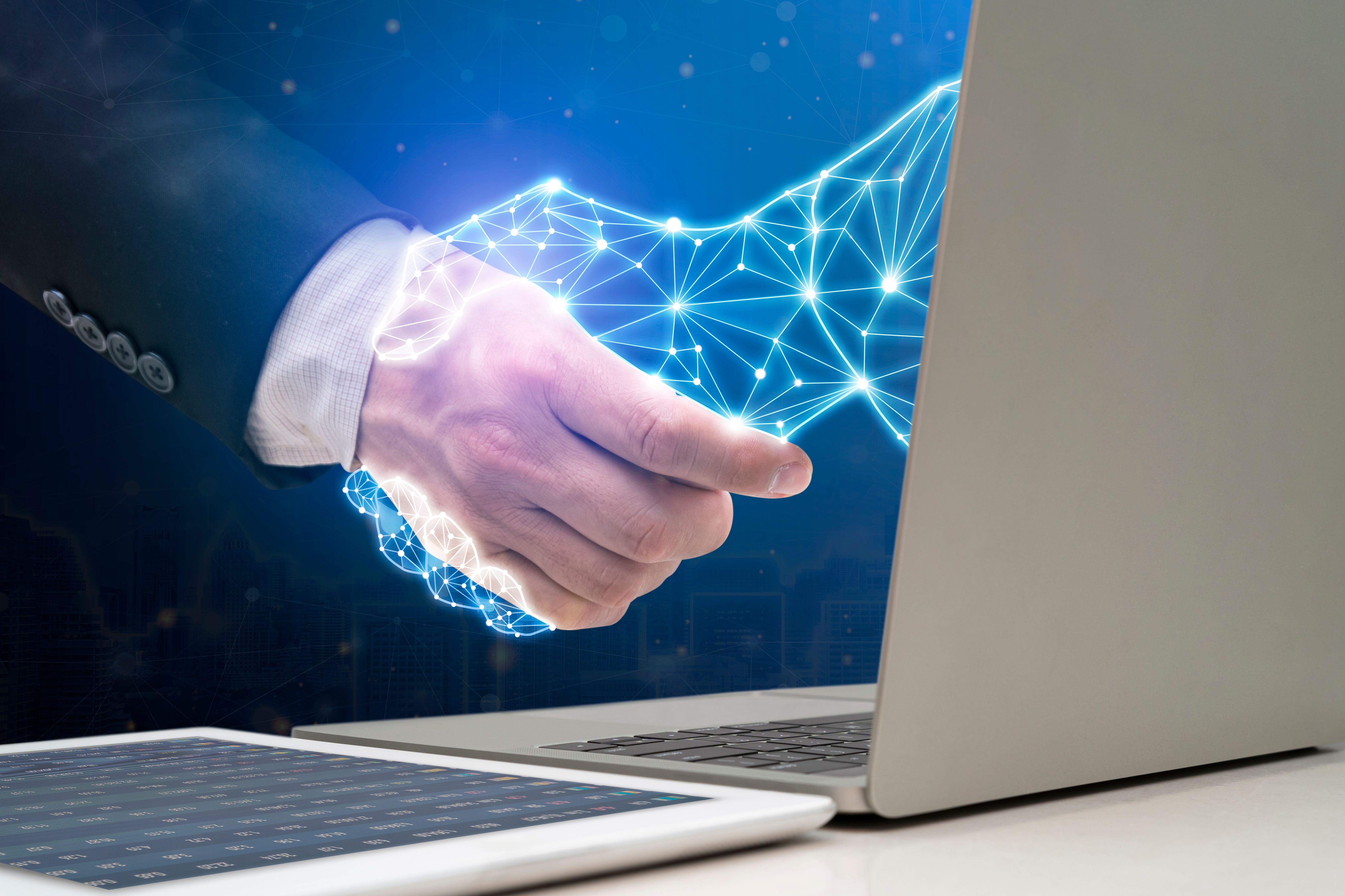 Businessman shaking hands with digital partner extending from laptop computer on futuristic background. Businessman shaking hands with digital partner extending from laptop computer on futuristic background.