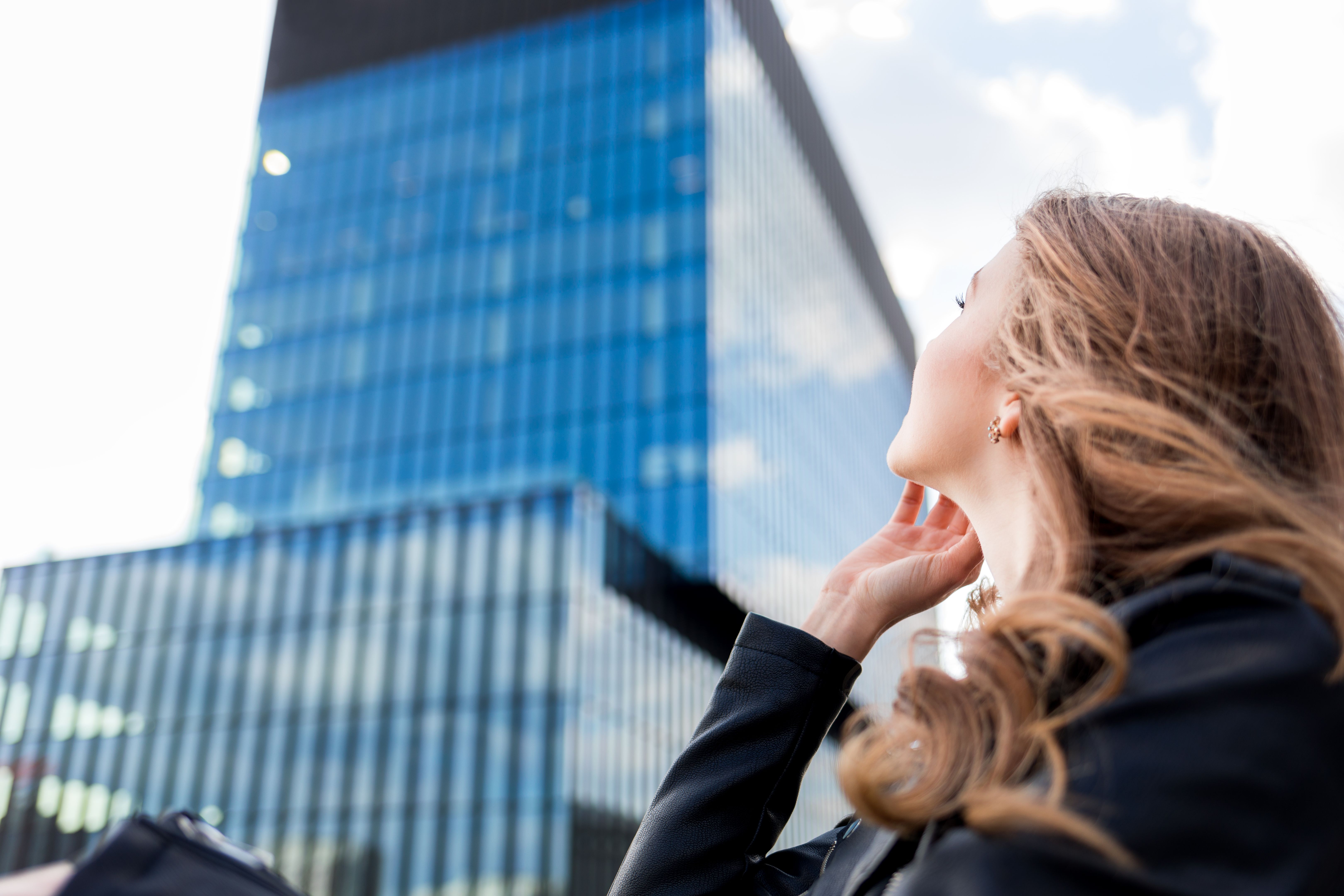 Beautiful smiling woman looking at modern office buildings in modern city Beautiful smiling woman looking at modern office buildings in modern city
