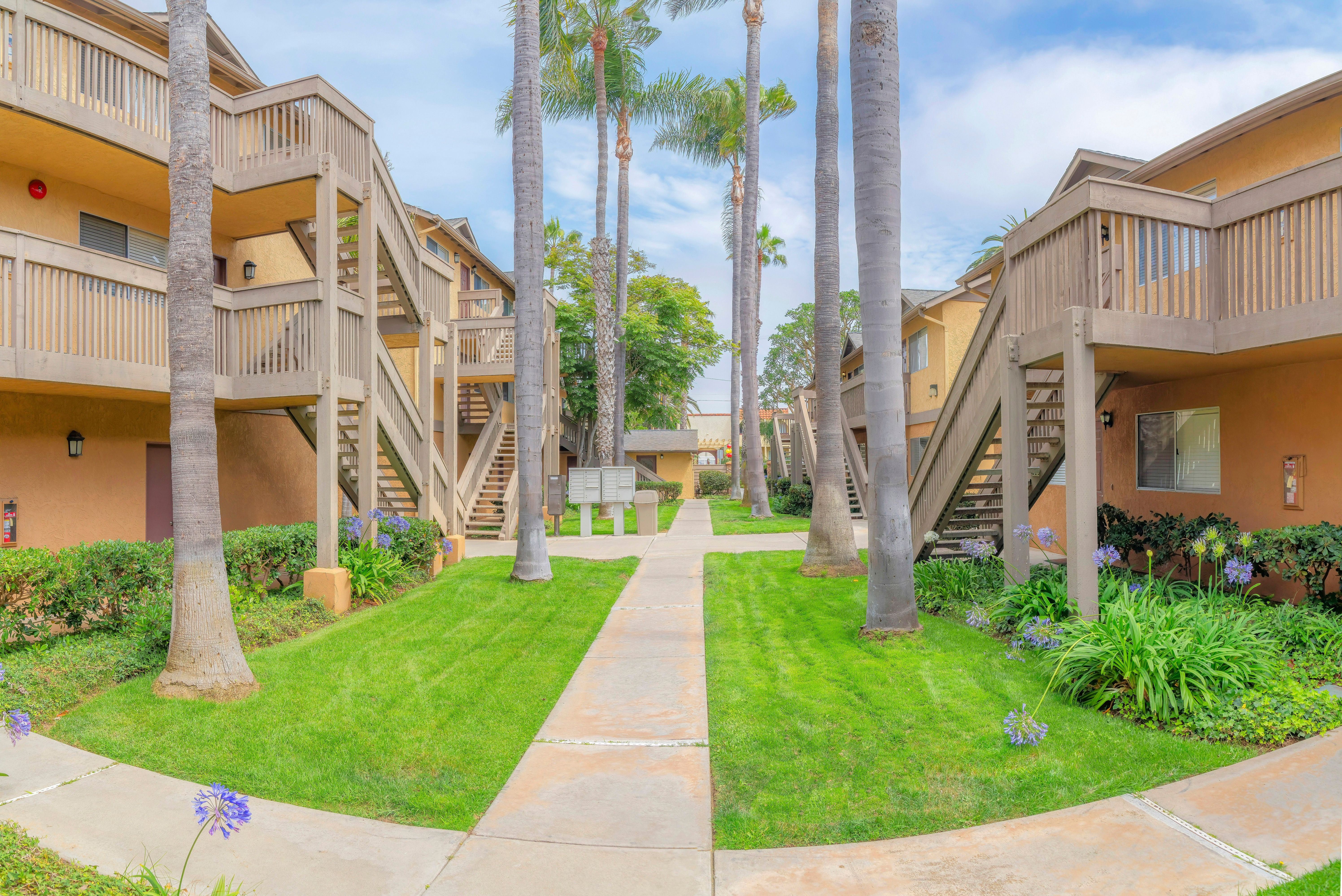 Apartment complex buildings with concrete path and pedestal mailboxes in the middle