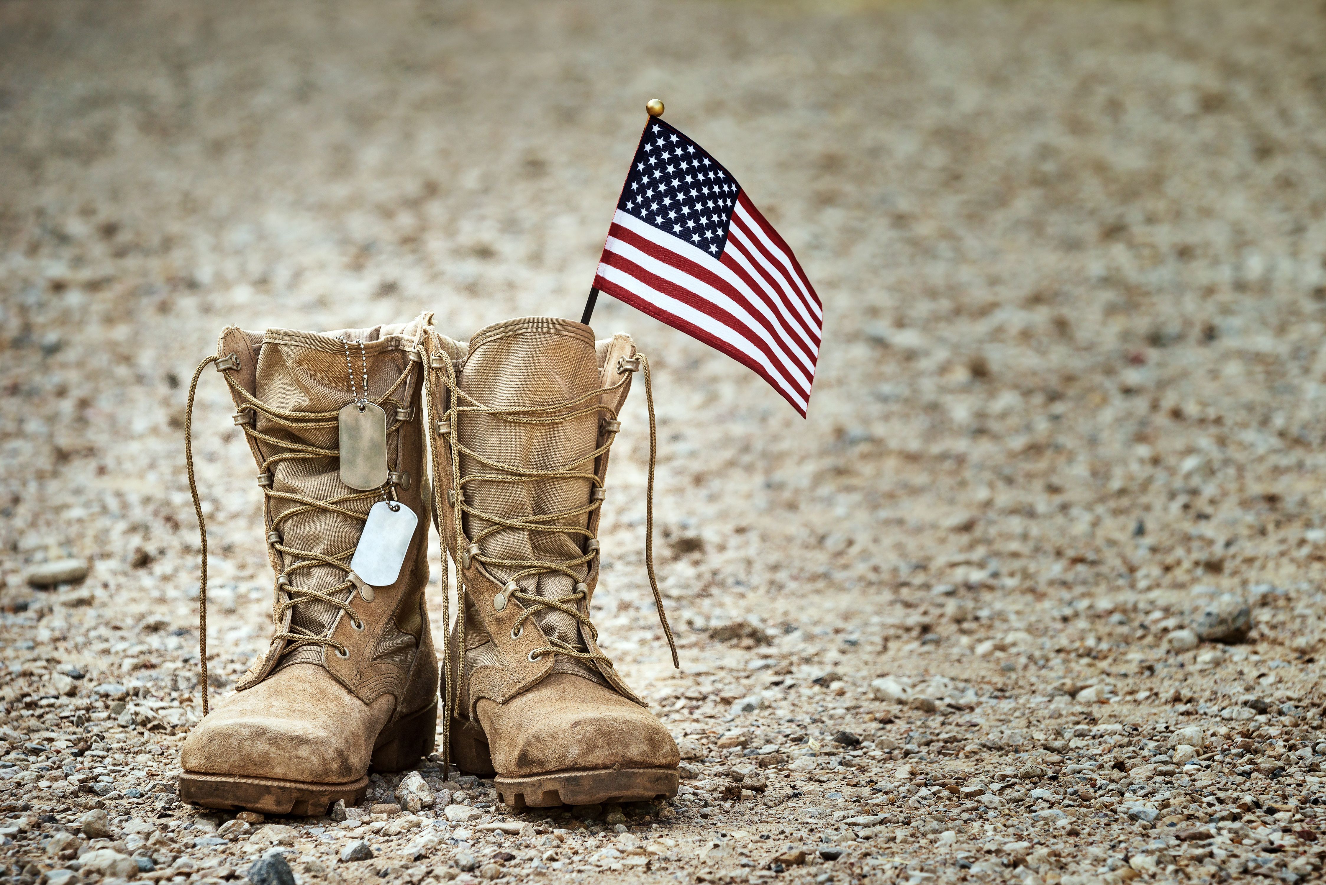 Old military combat boots with dog tags and a small American flag Old military combat boots with dog tags and a small American flag