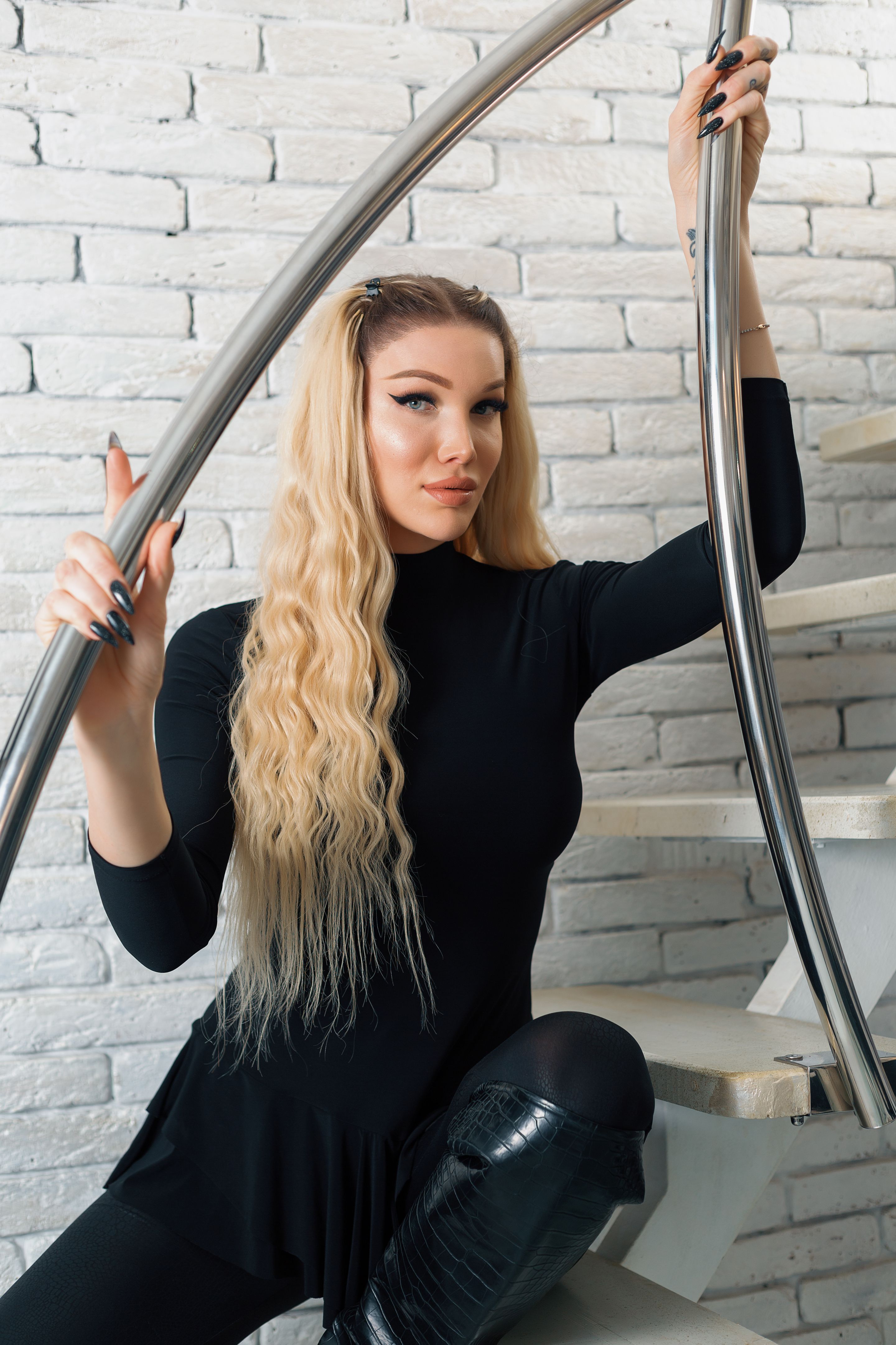 Beautiful blondie sitting on stairs and posing at camera