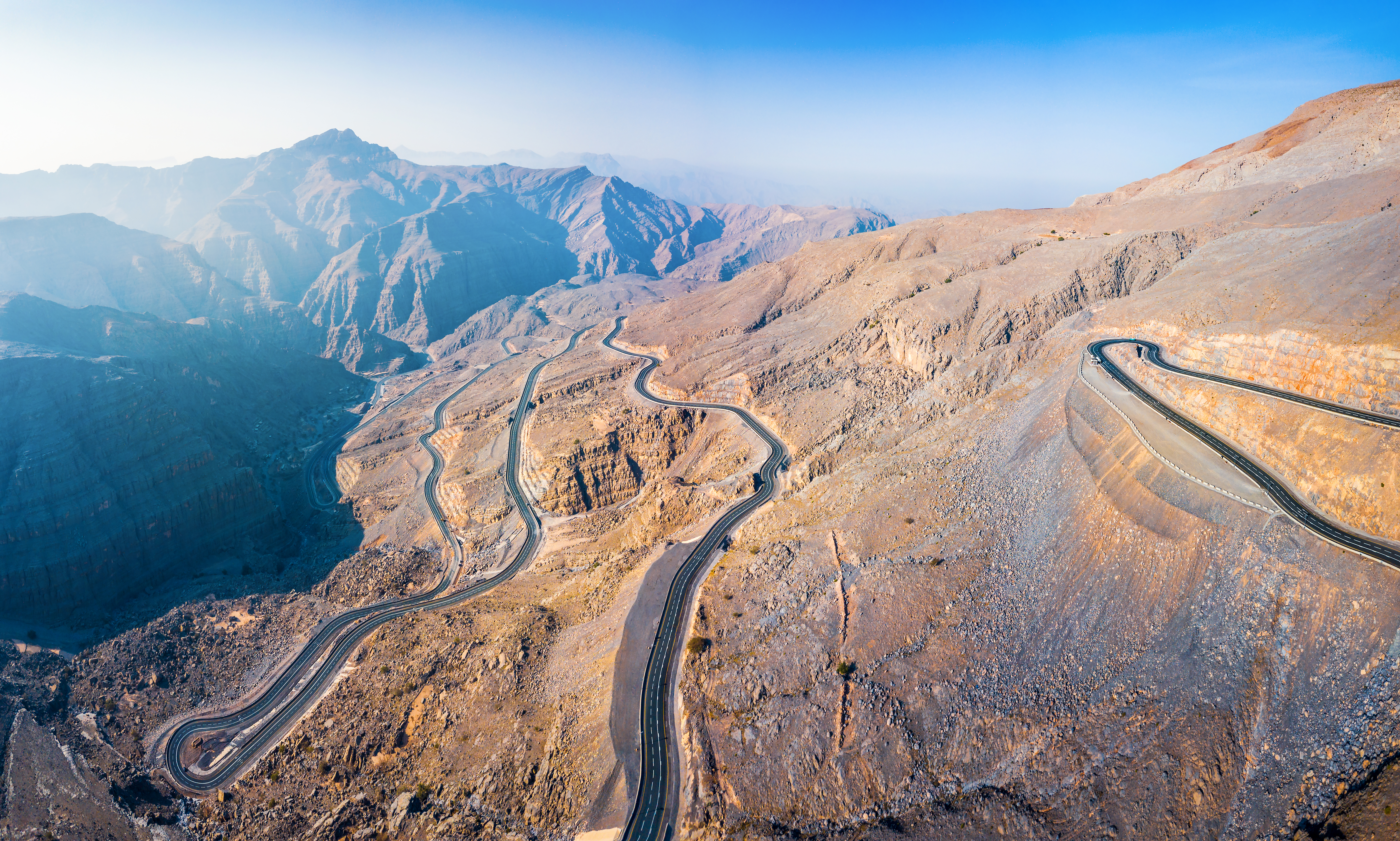 Panoramic view of winding desert road on Jebel Jais sandstone mountain in Ras Al Khaimah emirate or UAE