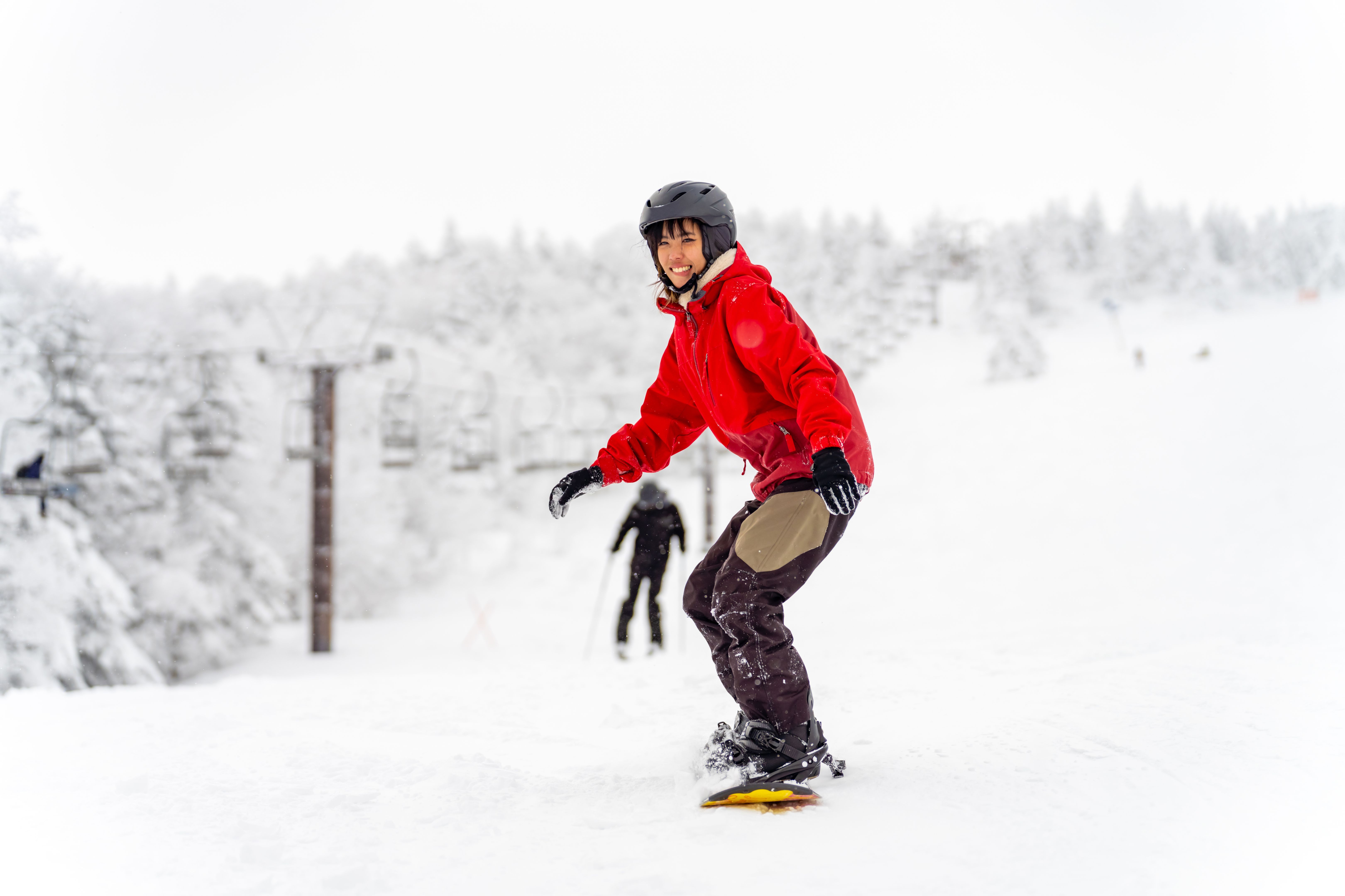 Asian woman practice snowboarding at ski slope