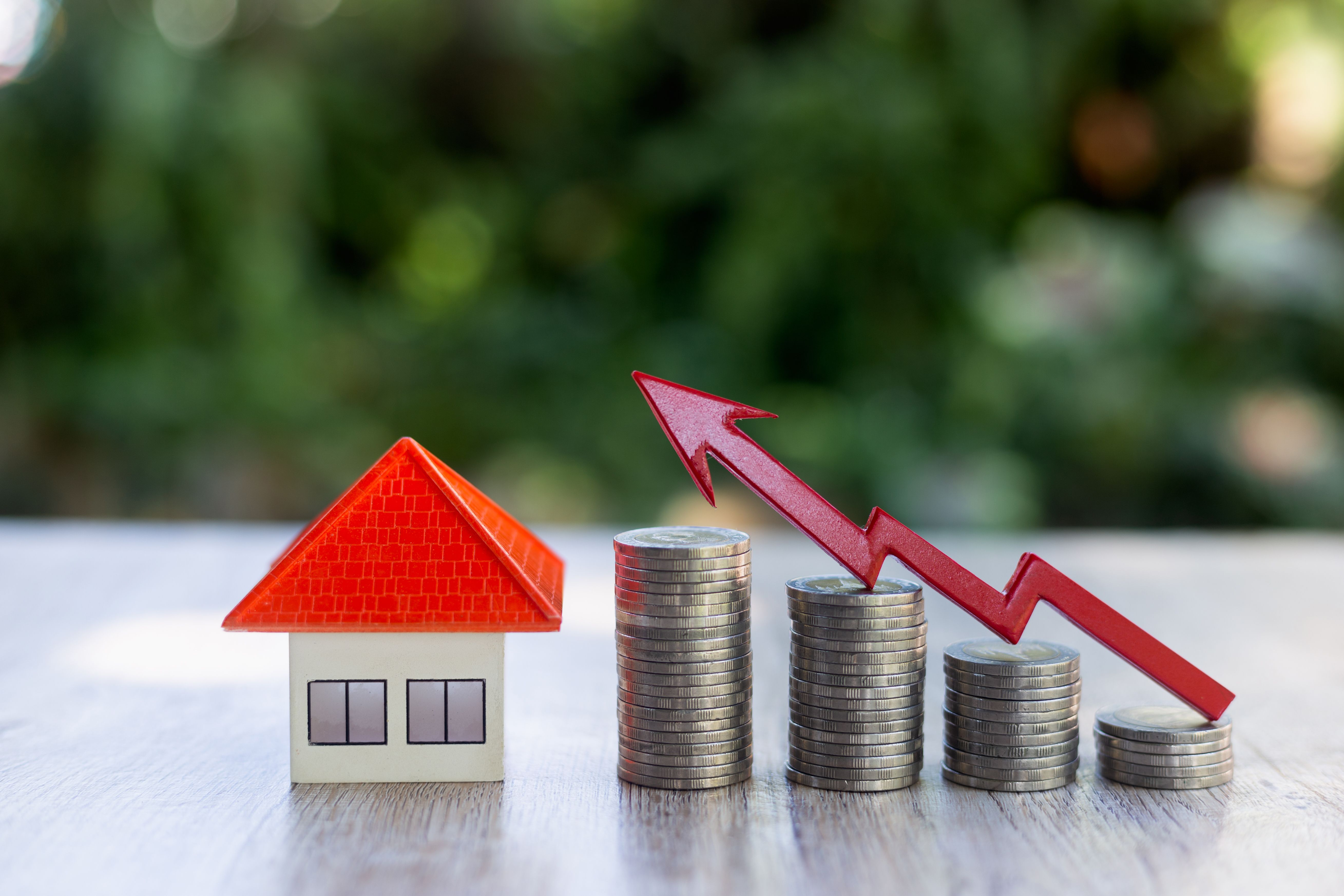 Casa de techo naranja Una flecha roja en la escalera de la moneda de negocios Monedas para comprar ideas de casas Gráfico financiero Crecimiento inmobiliario.