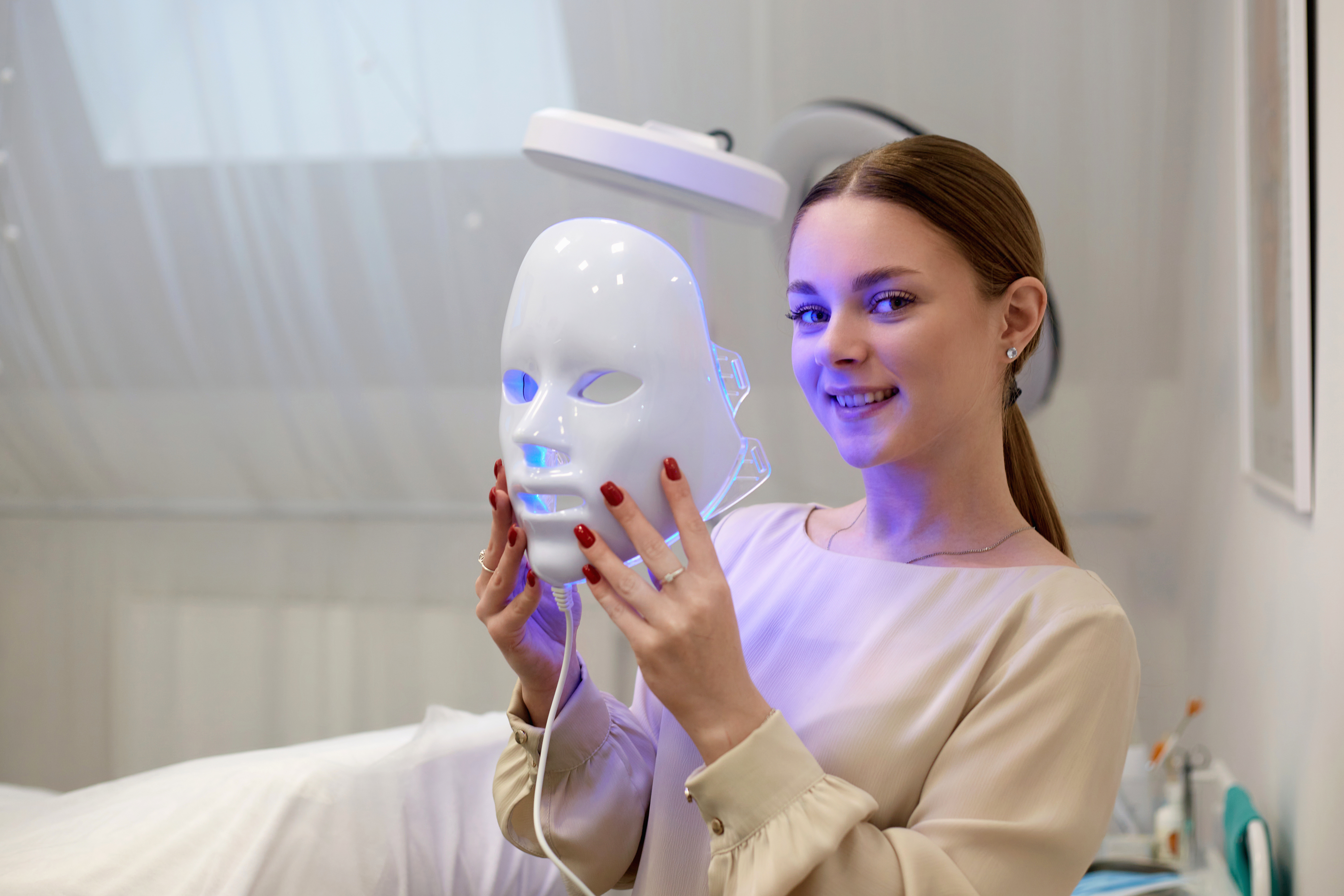 Beautiful young woman getting a led light therapy mask treatment for her face