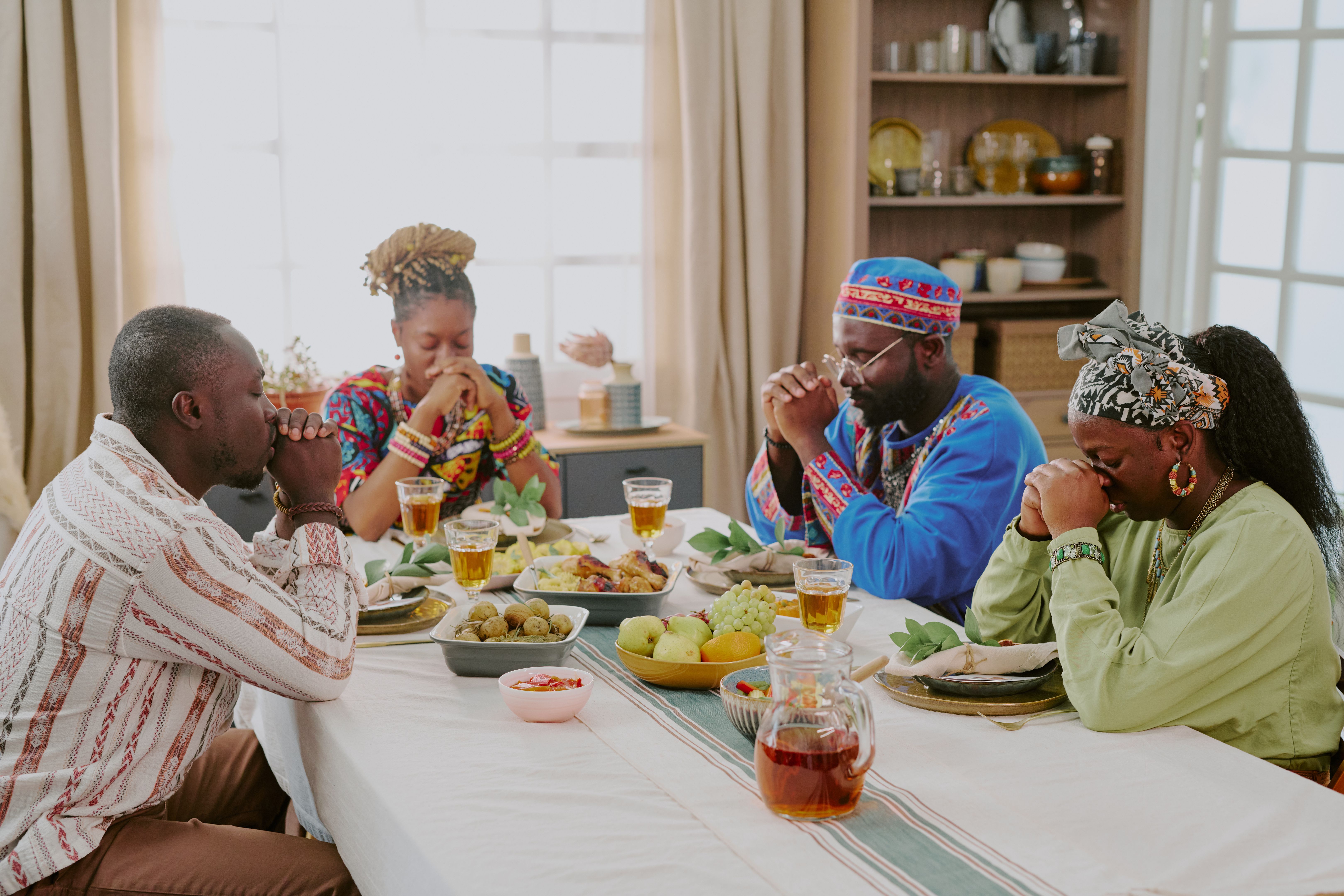 Black Family Praying Together before Meal during Kwanzaa Celebration Indoors Black Family Praying Together before Meal during Kwanzaa Celebration Indoors