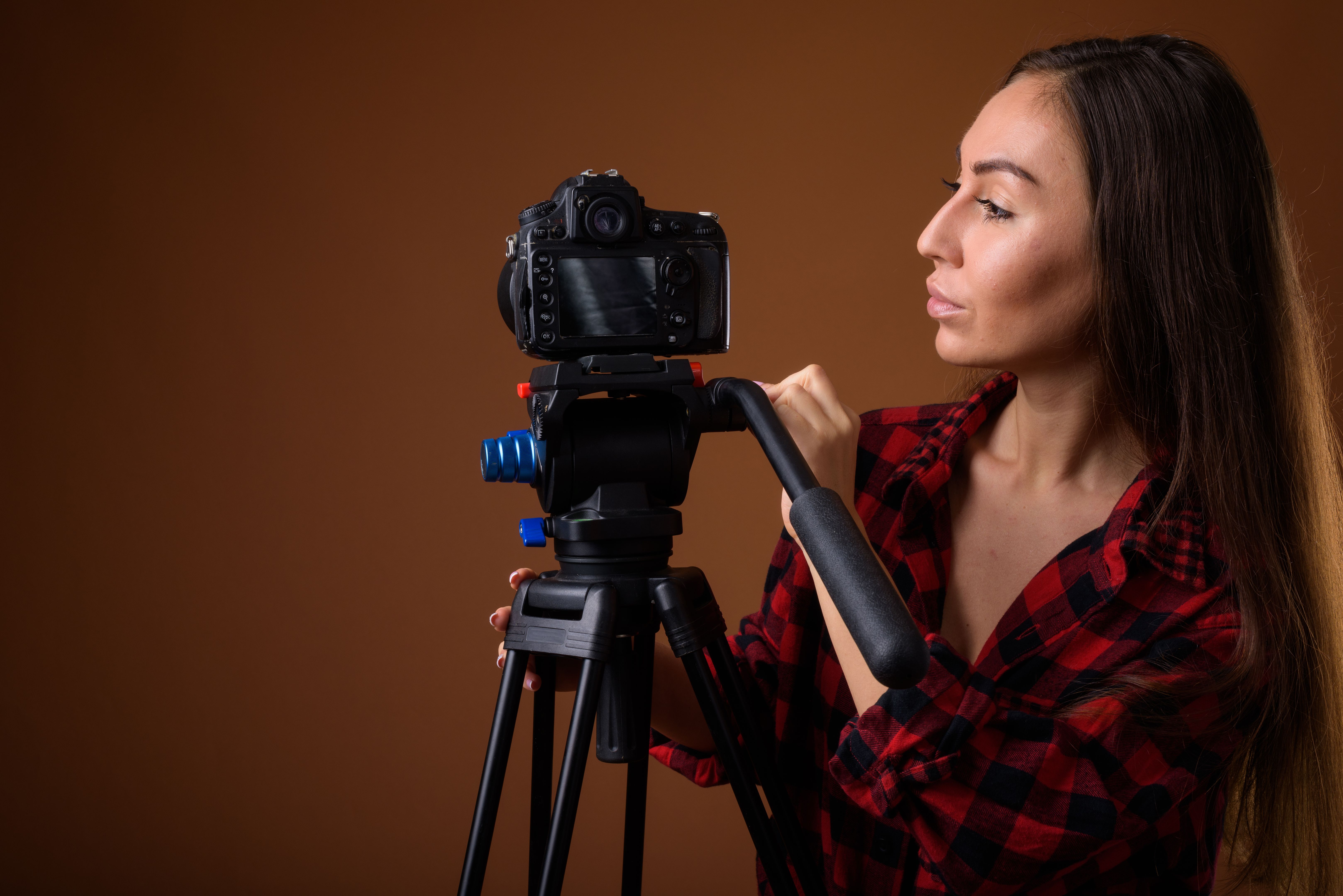 Studio shot of young beautiful woman getting ready for vlogging against colored background