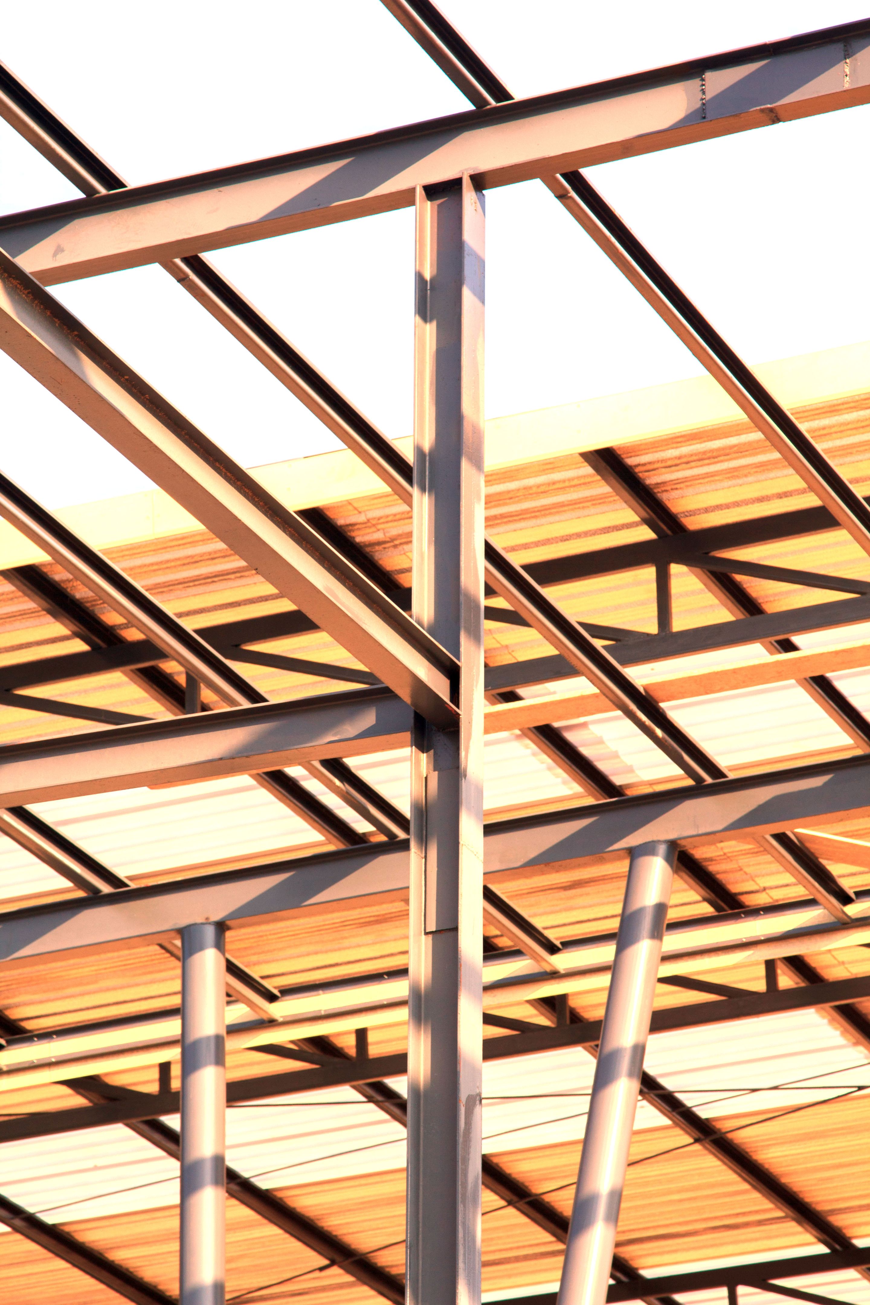 Metal roof structure on a modern building with a metal ladder on the wall and roof against the sky, highlighting architectural design