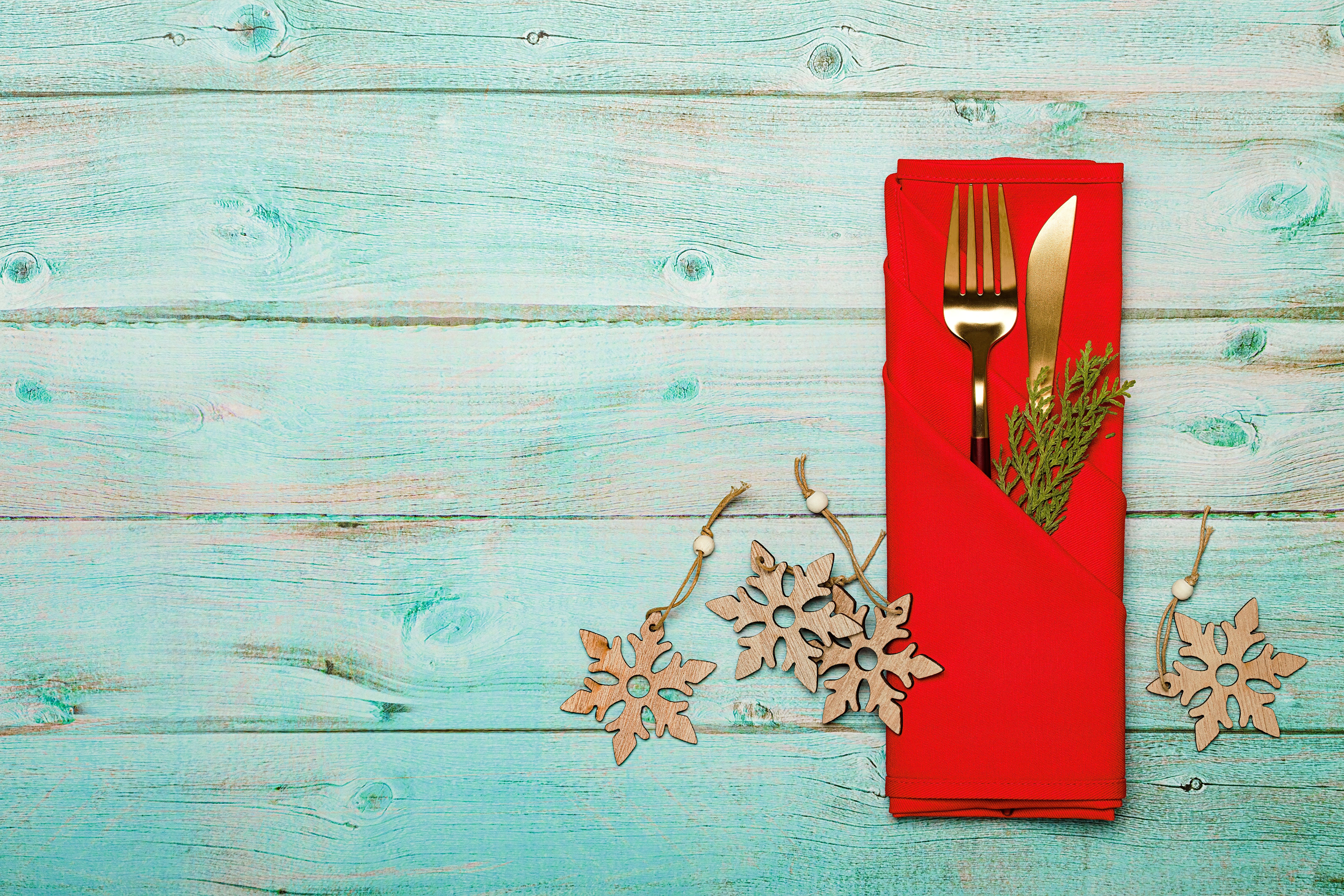 Cutlery tablecloth and snowflake symbol on wooden board. Holiday Christmas food background concept. Christmas table setting with a set of cutlery knife and fork on a red napkin with xmas decorations.  Christmas menu concept.