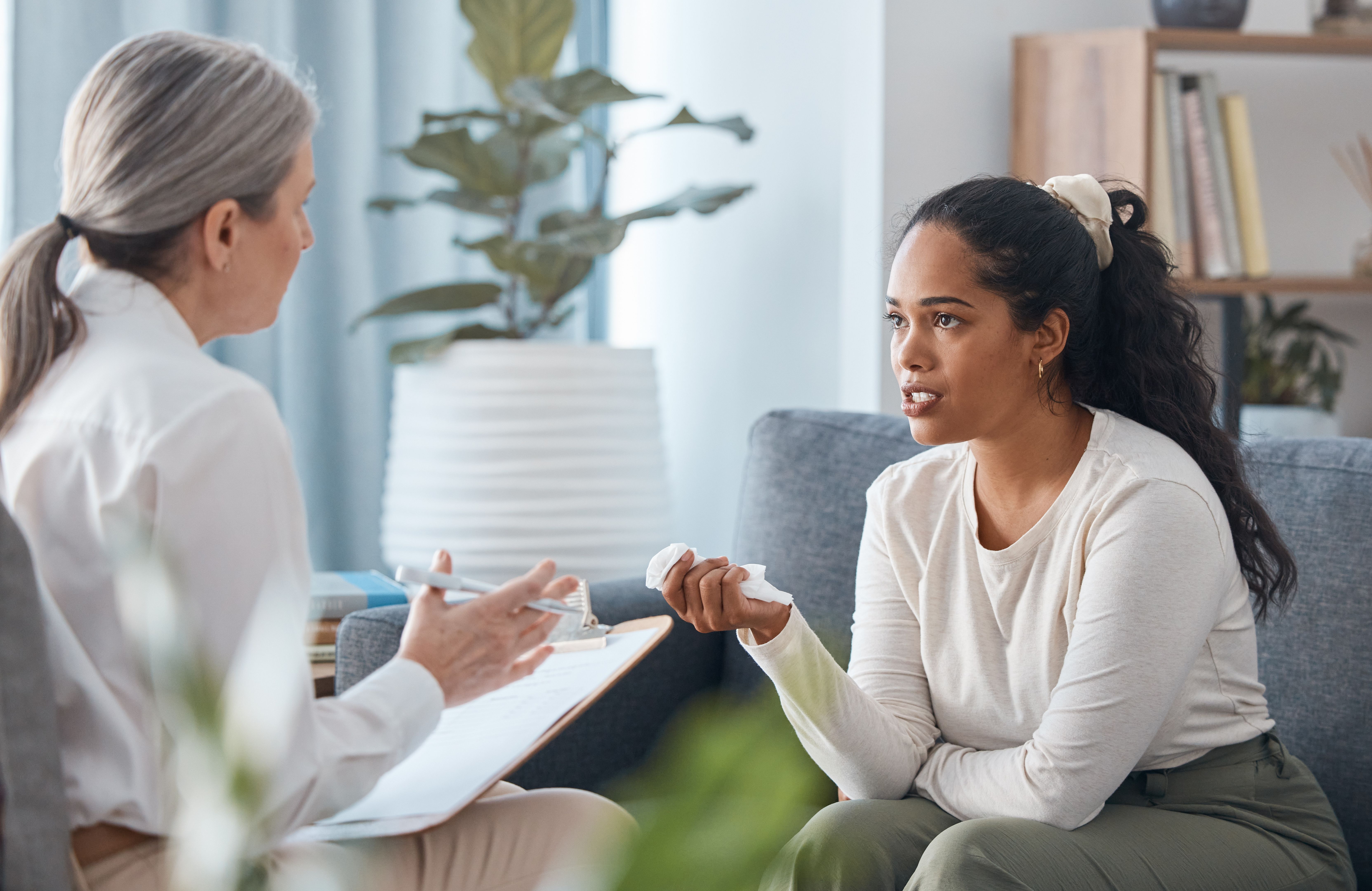 Shot of an attractive young woman sitting and talking to her psychologist during a consultation Shot of an attractive young woman sitting and talking to her psychologist during a consultation