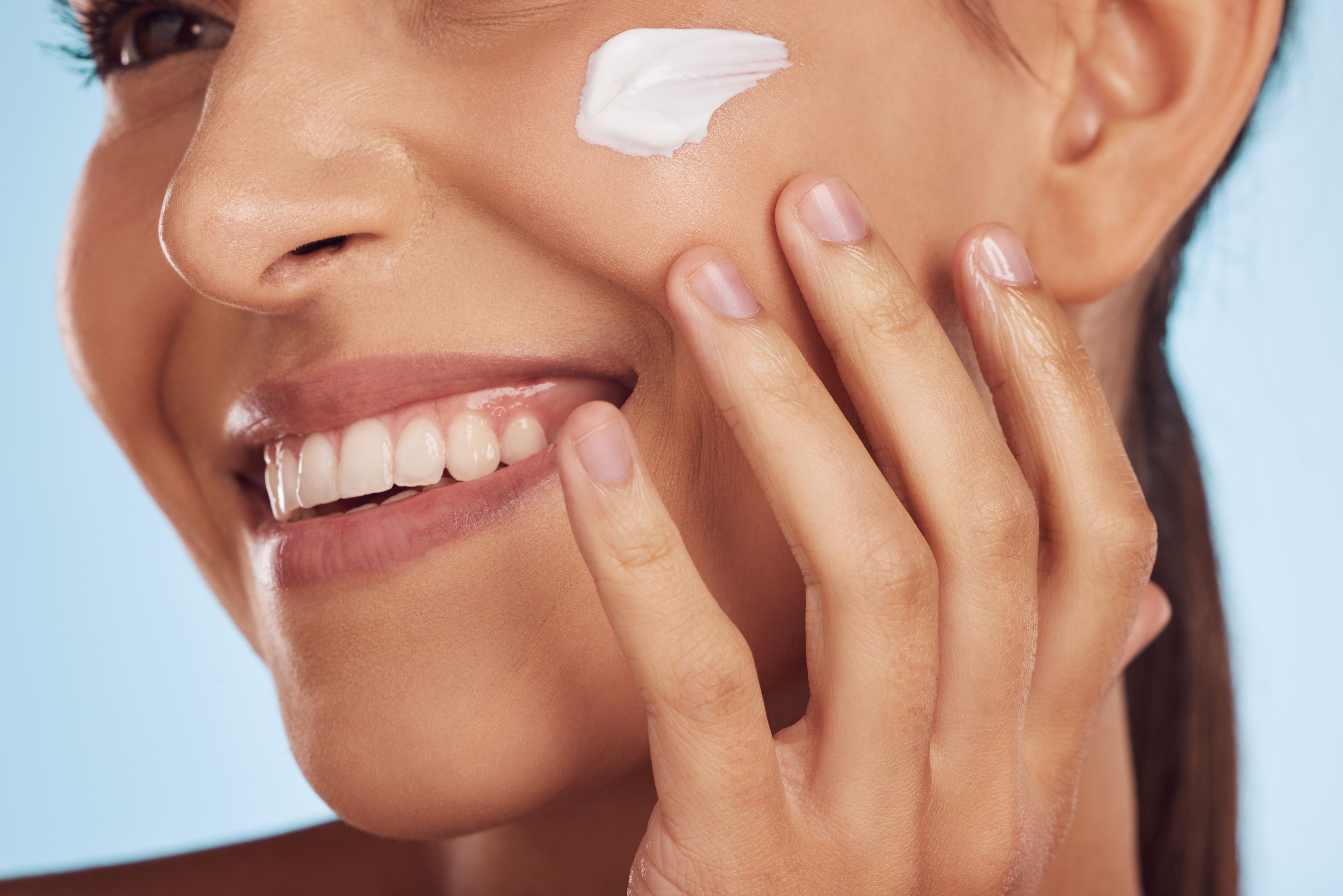 Face, beauty and woman with cream, closeup and cosmetics on a blue studio background. Self care, female person and model with lotion, skincare and dermatology with creme, aesthetic and luxury product Face, beauty and woman with cream, closeup and cosmetics on a blue studio background. Self care, female person and model with lotion, skincare and dermatology with creme, aesthetic and luxury product