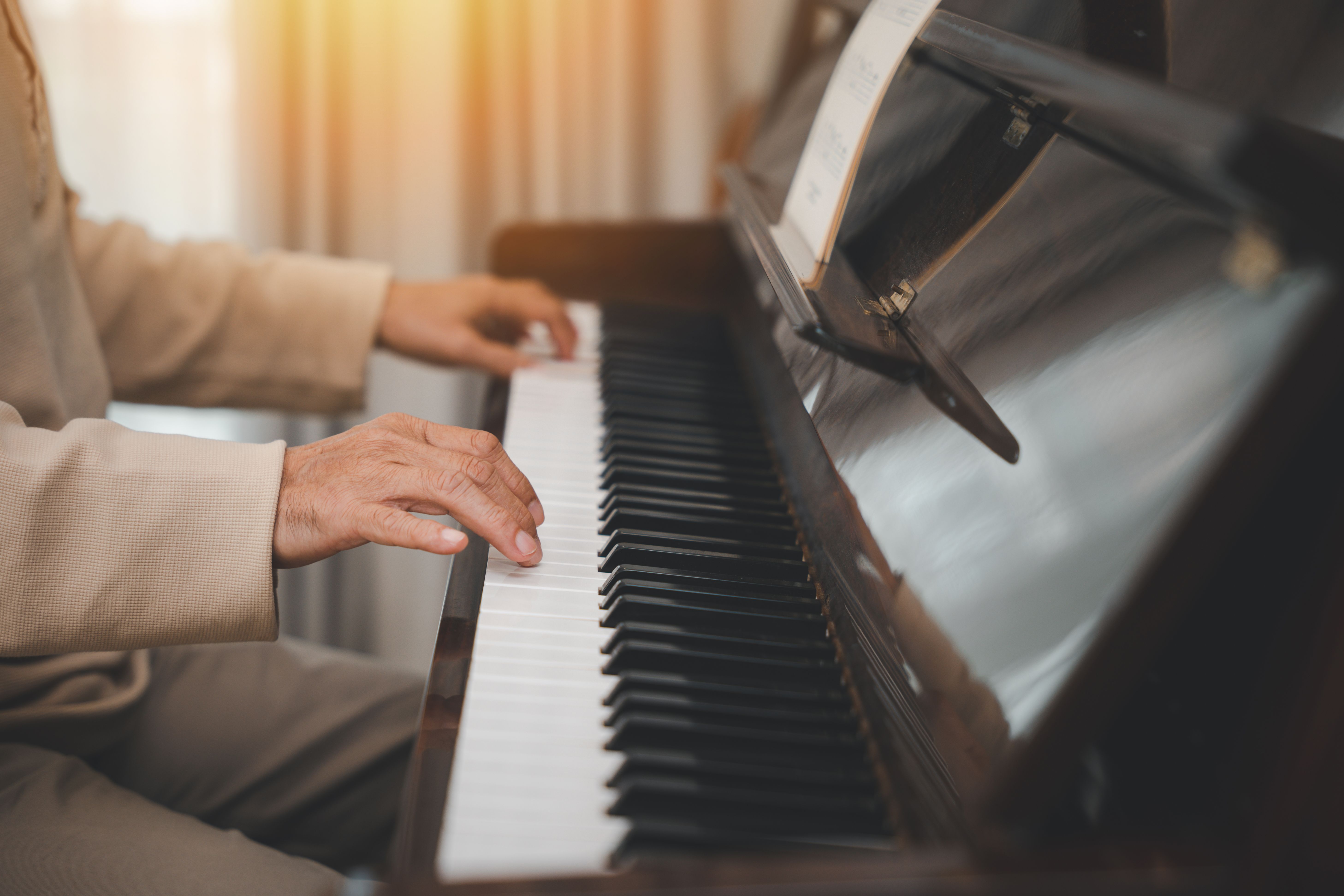 senior retirement man with eyeglasses learn to play piano at home