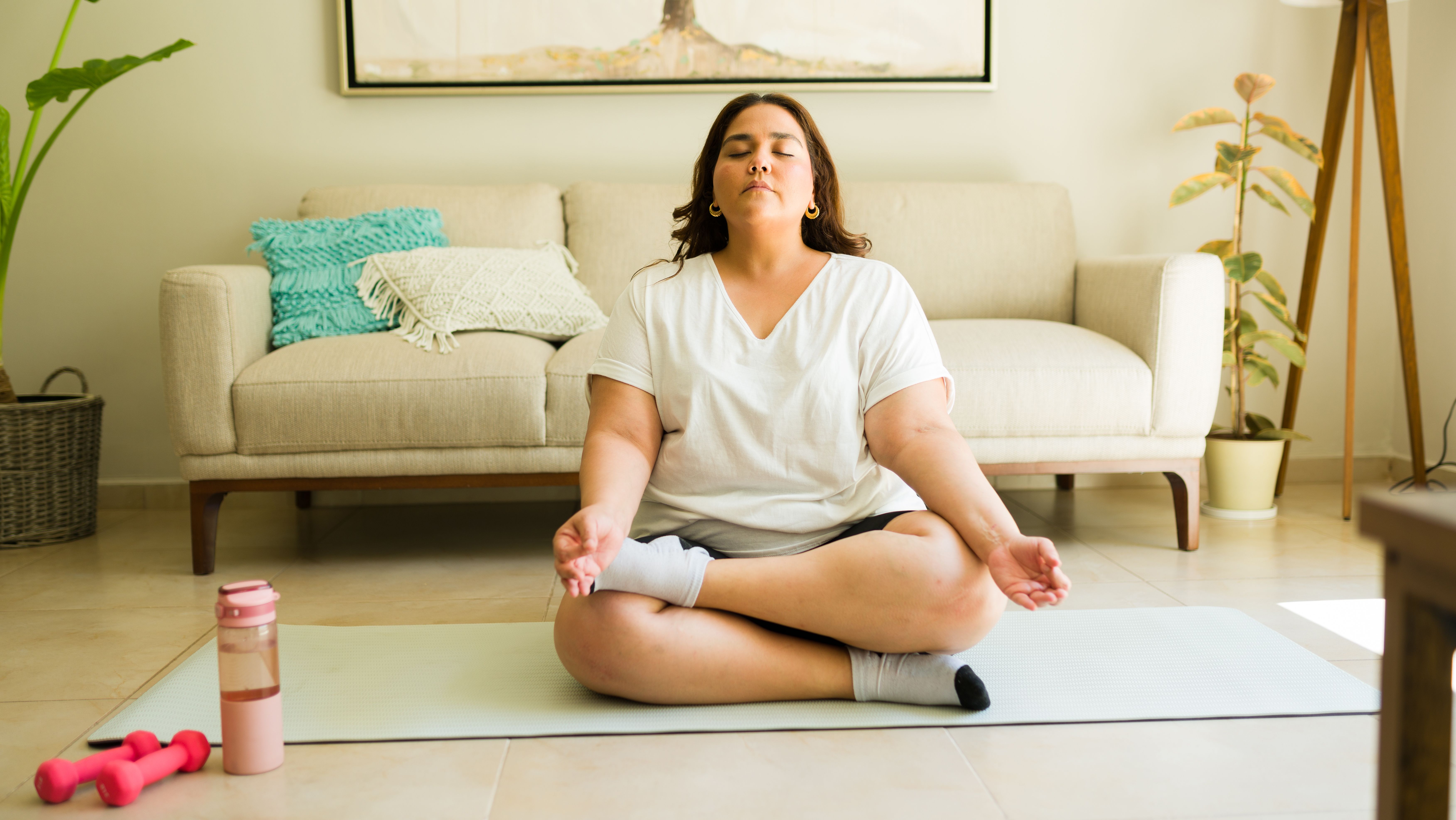 Woman embracing self-care and body positivity through a mindfulness meditation exercise in her living room Woman embracing self-care and body positivity through a mindfulness meditation exercise in her living room