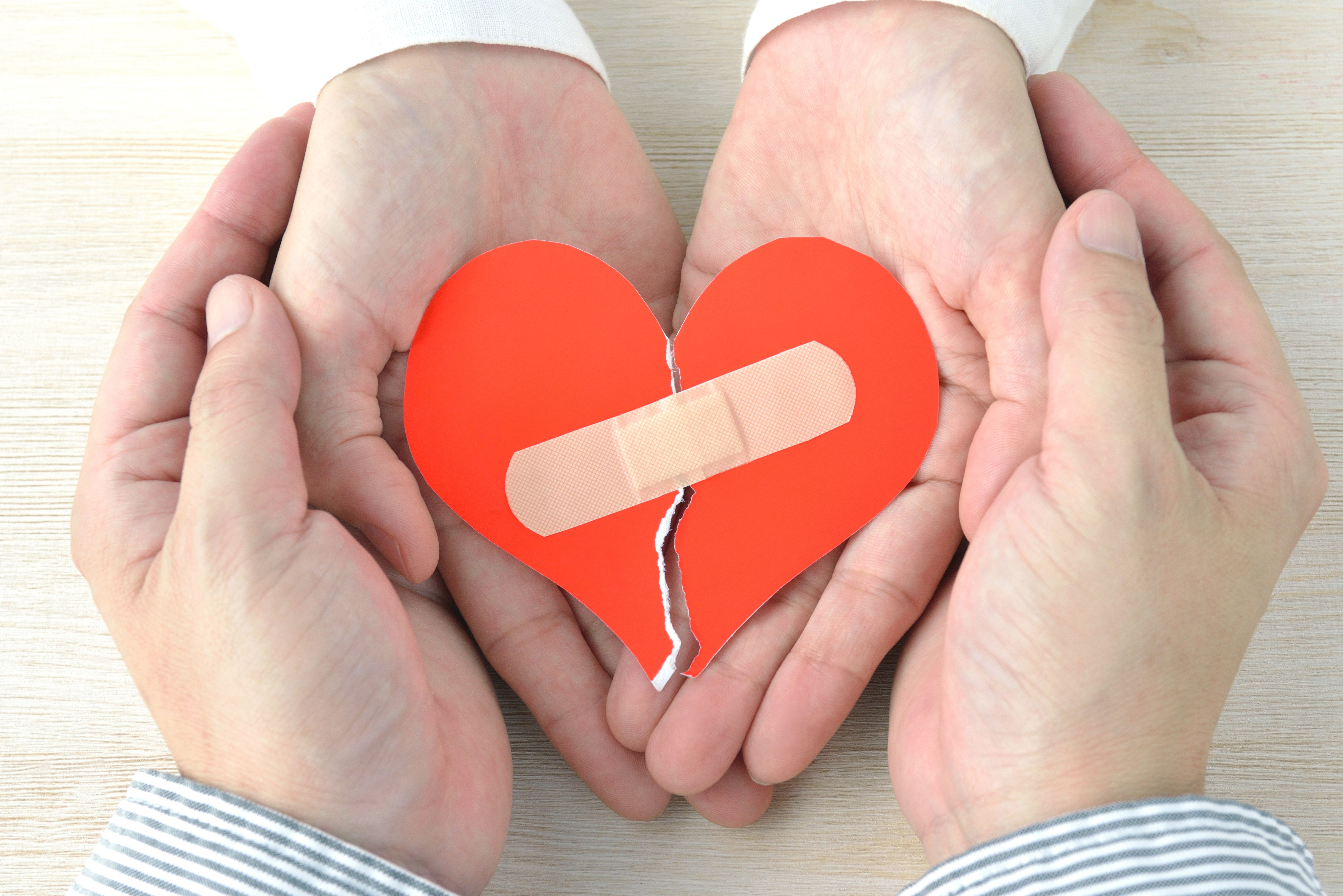 Couple's hands having broken heart with adhesive plaster Couple's hands having broken heart with adhesive plaster