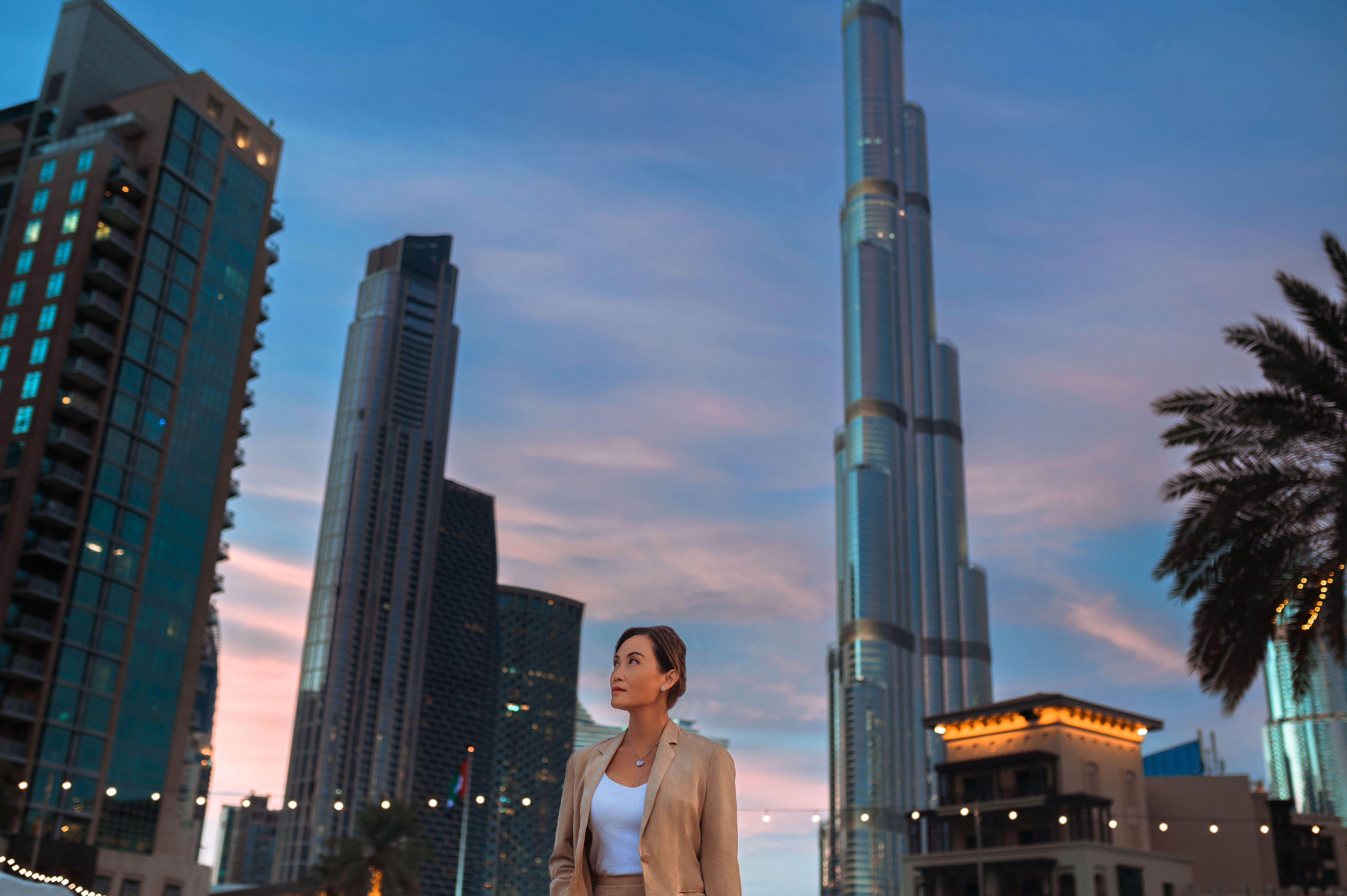 Low angle view of contemplative businesswoman admiring skyscrapers in city center at night