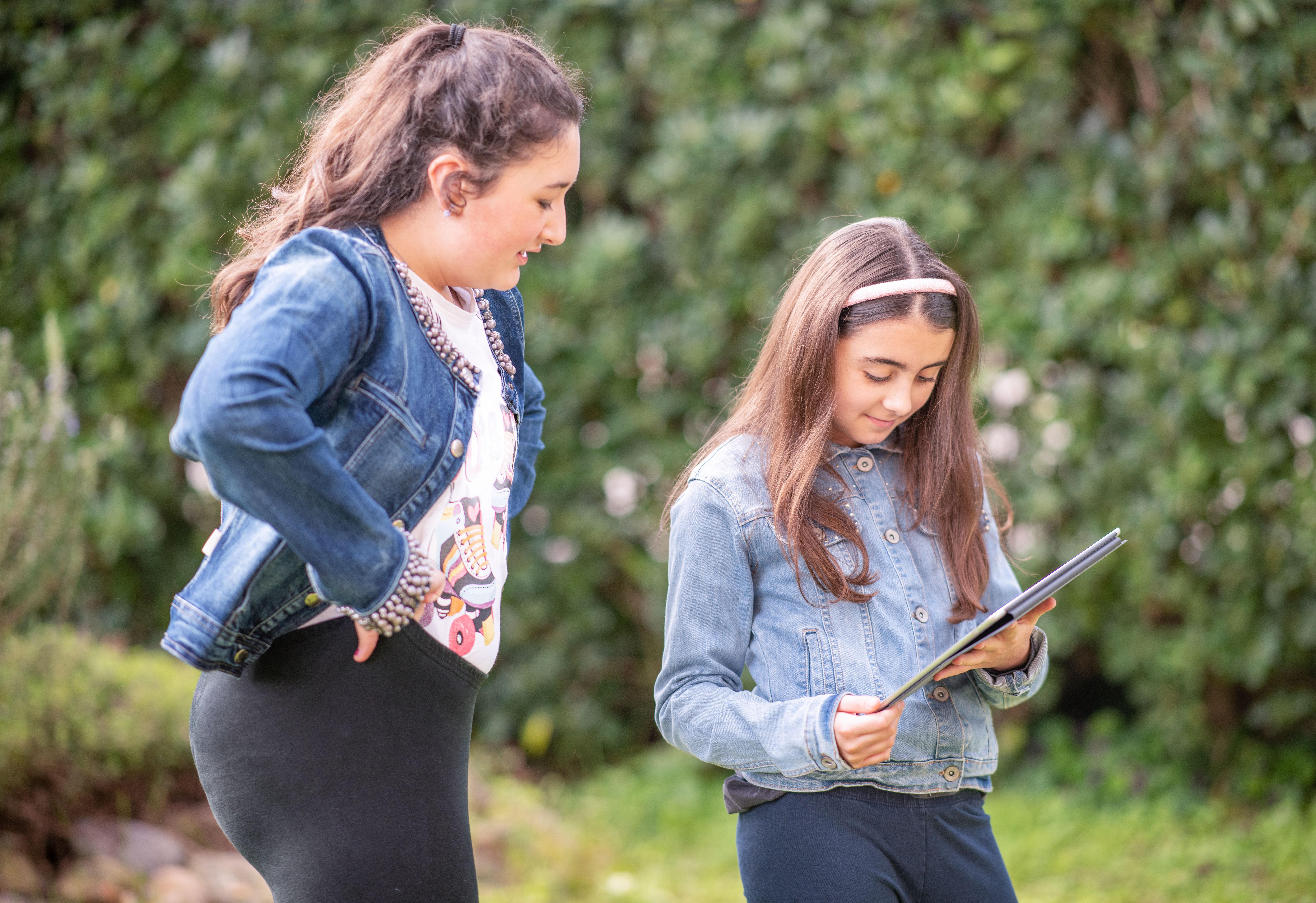 Teenagers using social media. School girls having fun outdoors. Surfing the net on tablets, 
watching a social media live stream