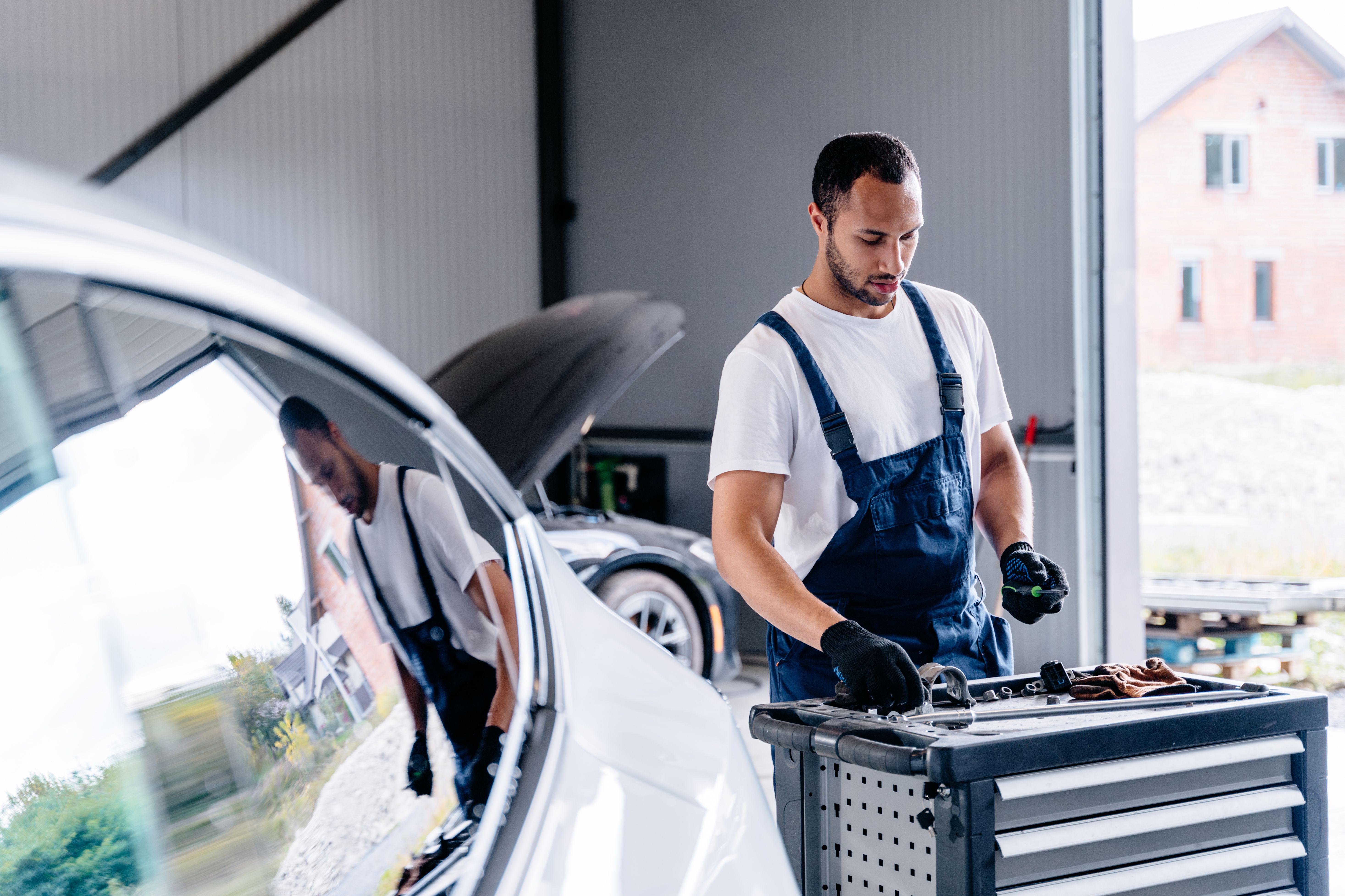 Car diagnostic service concept. Modern mechanic work in garage. Auto mechanic using computer software for diagnostics engine working and repairing car in a garage.