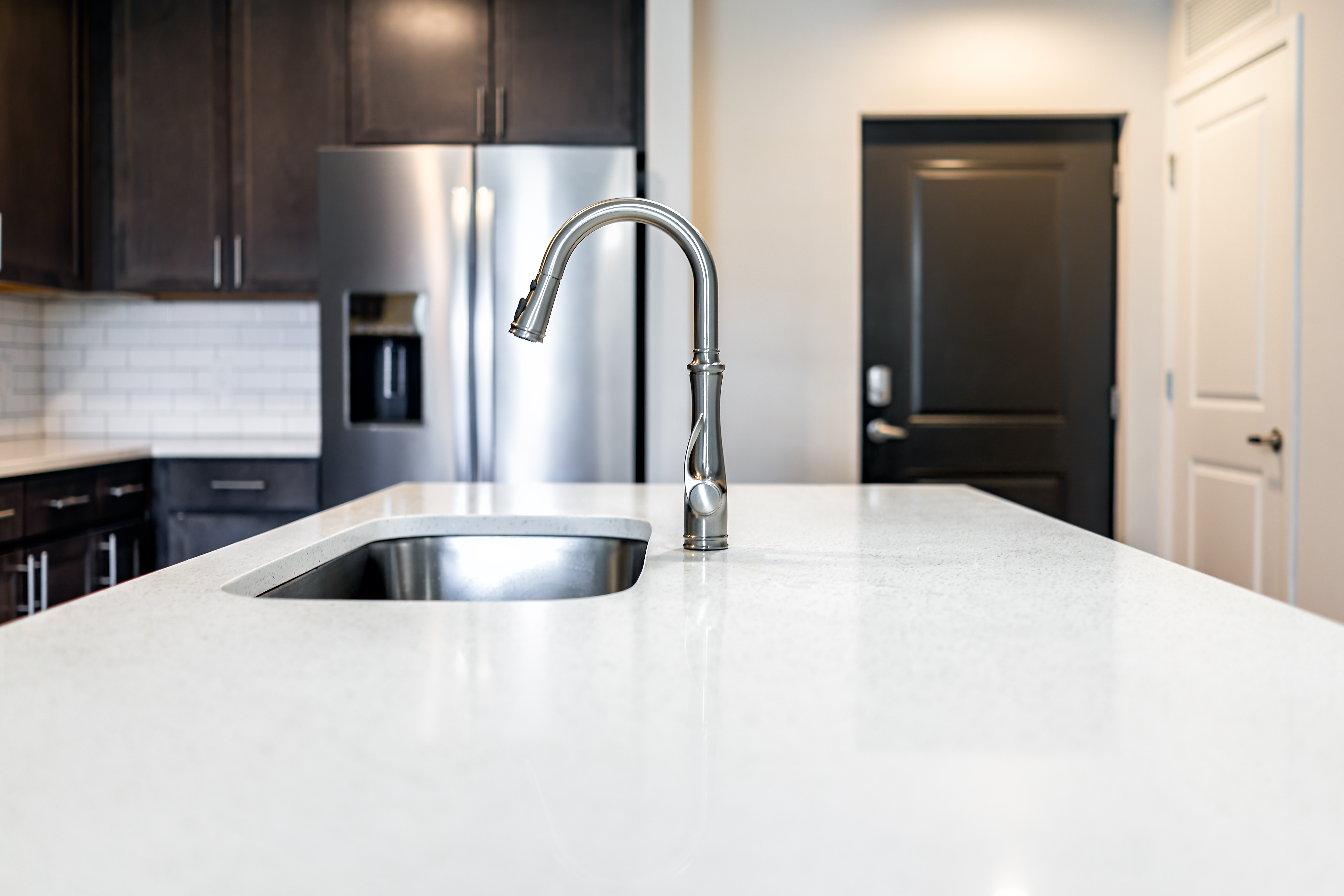 Kitchen room quartz countertop surface island in modern apartment home house by cabinets refrigerator fridge home appliance door entrance Kitchen room quartz countertop surface island in modern apartment home house by cabinets refrigerator fridge home appliance door entrance