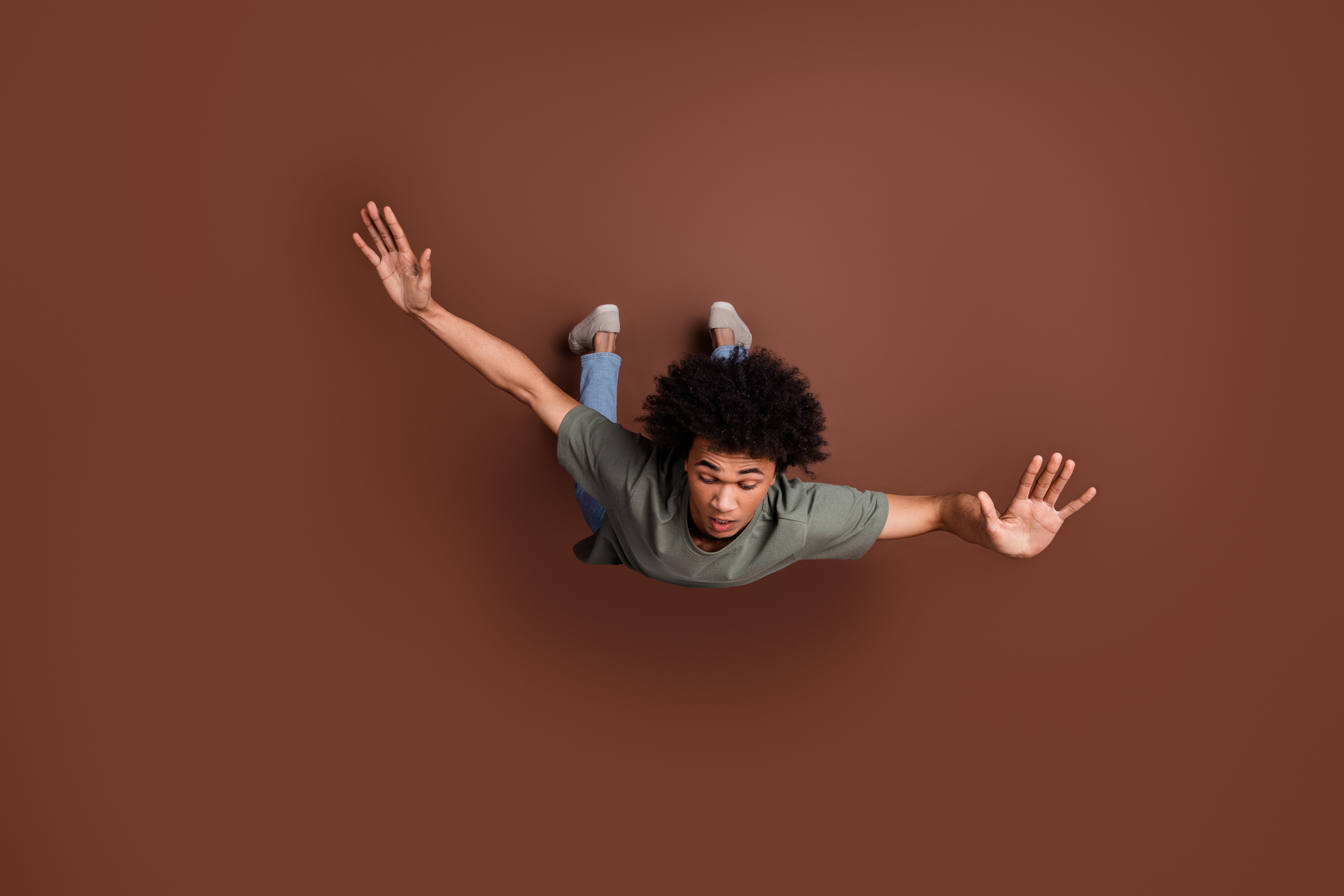 Full length photo of handsome young male falling down afraid dressed stylish khaki garment isolated on brown color background
