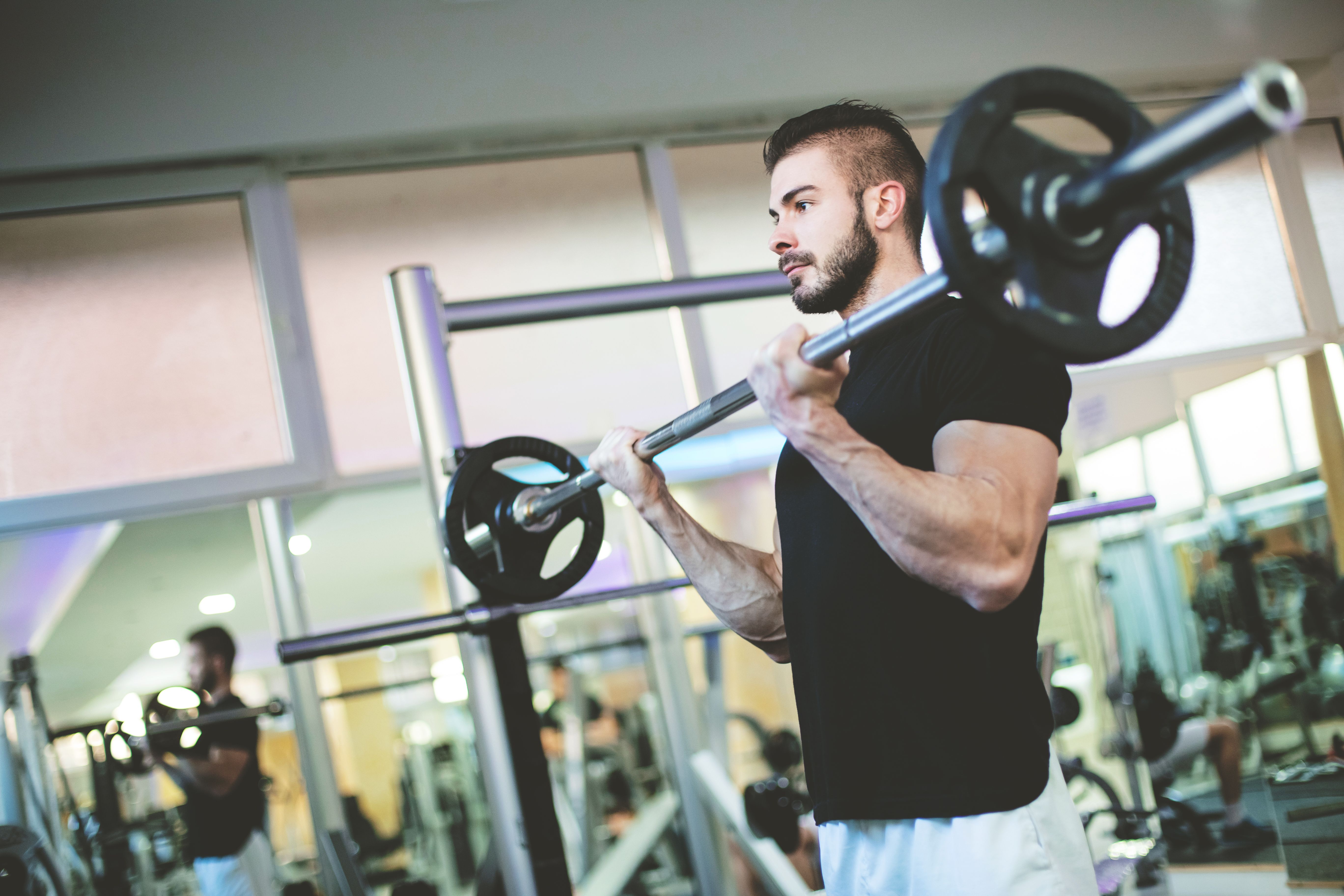Muscular Bodybuilder Men Doing Exercises with Dumbbells in Gym