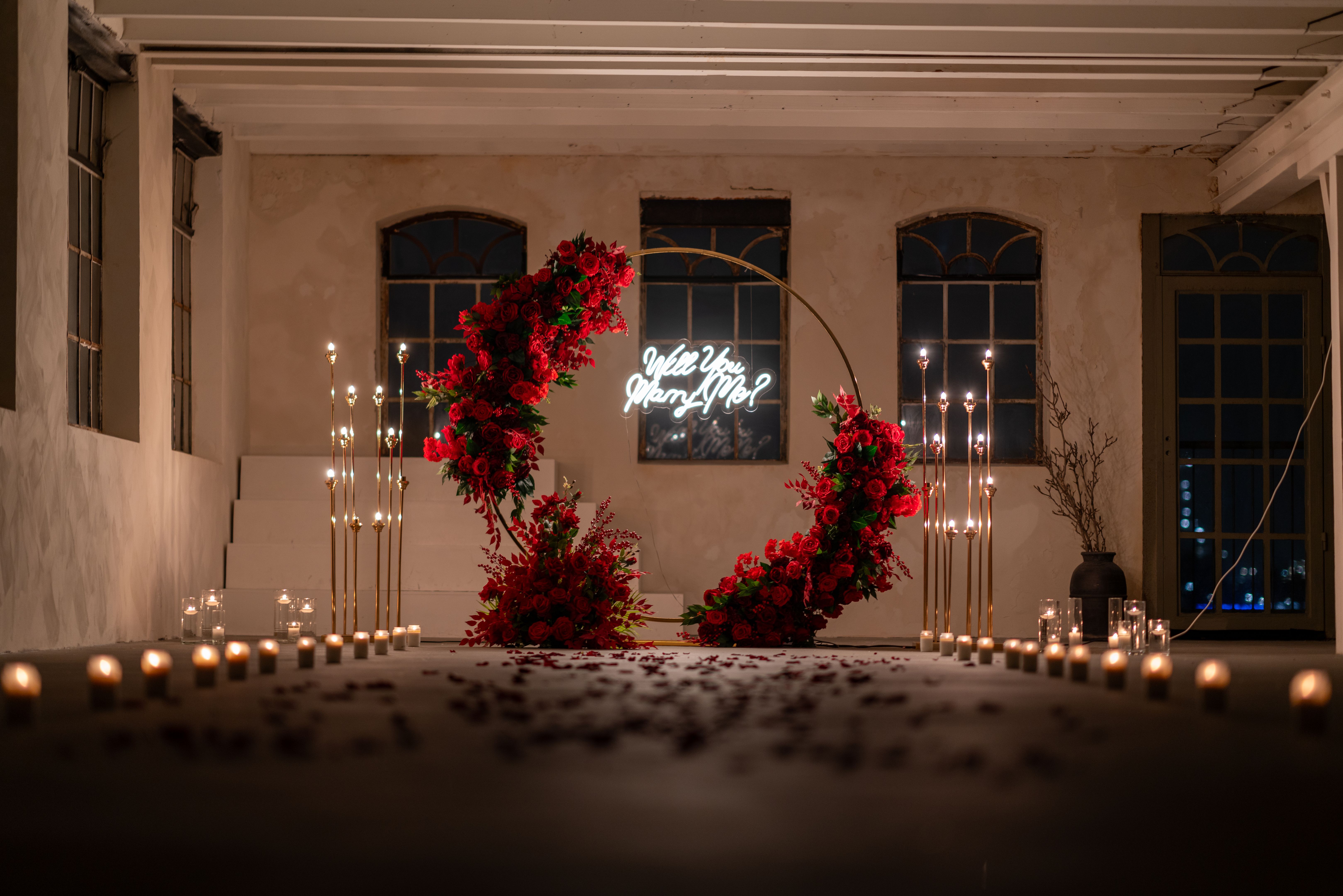Romantic marriage proposal setup with candles and red roses