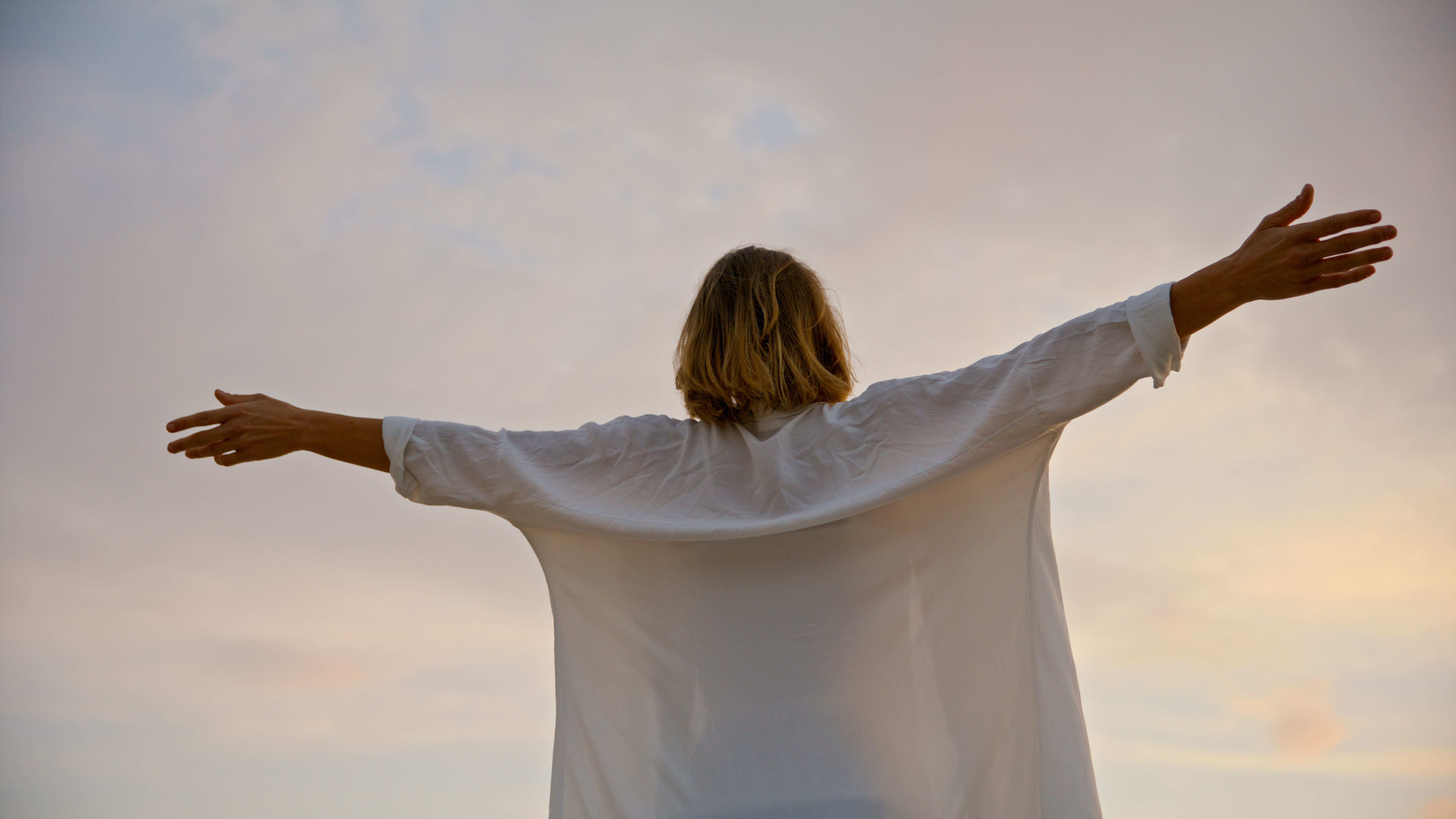 Rear view of carefree woman standing with arms outstretched against cloudy sky during sunset at Istria,Croatia