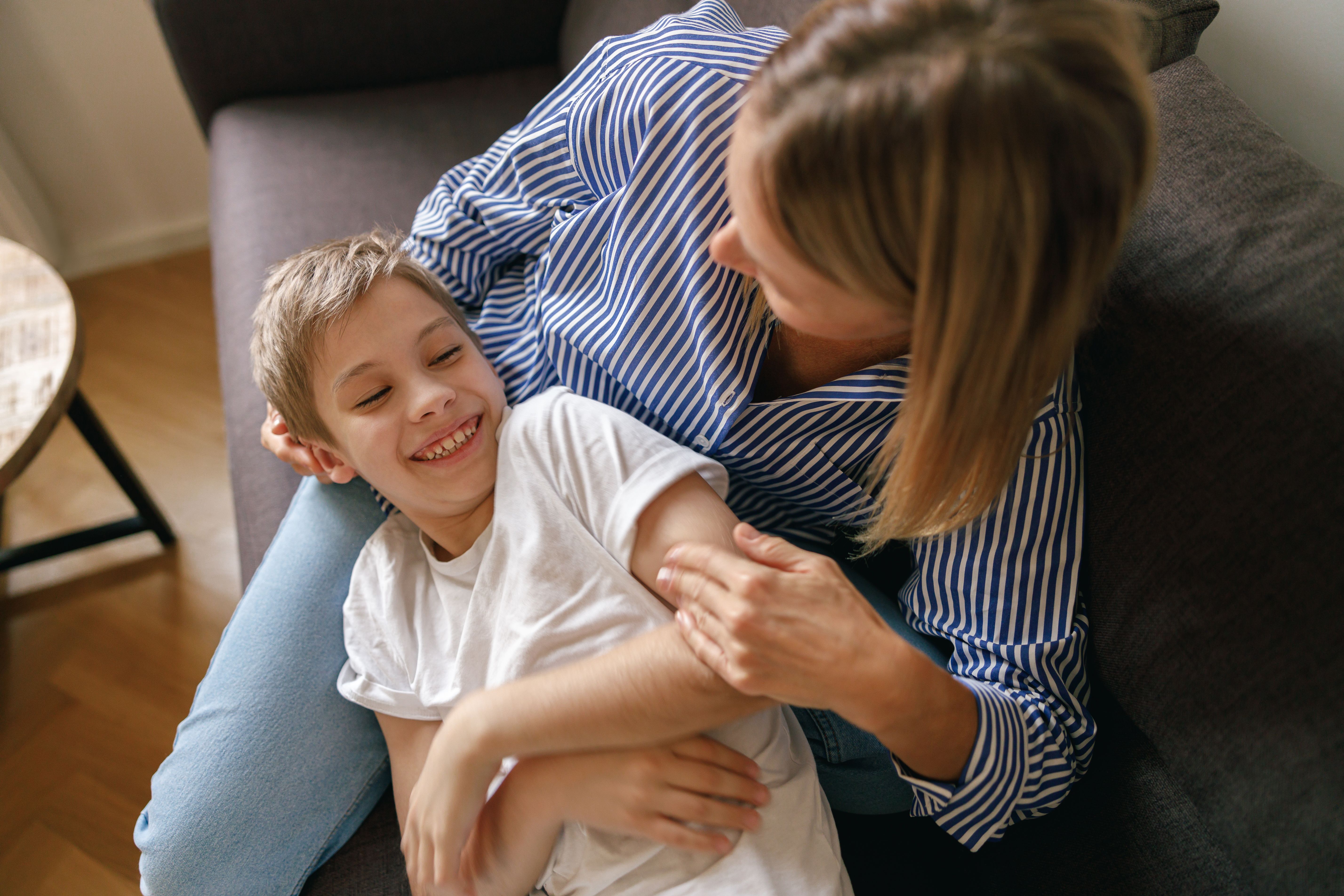 Mother and son plays tickle at home on the sofa living room. Happy motherhood and childhood