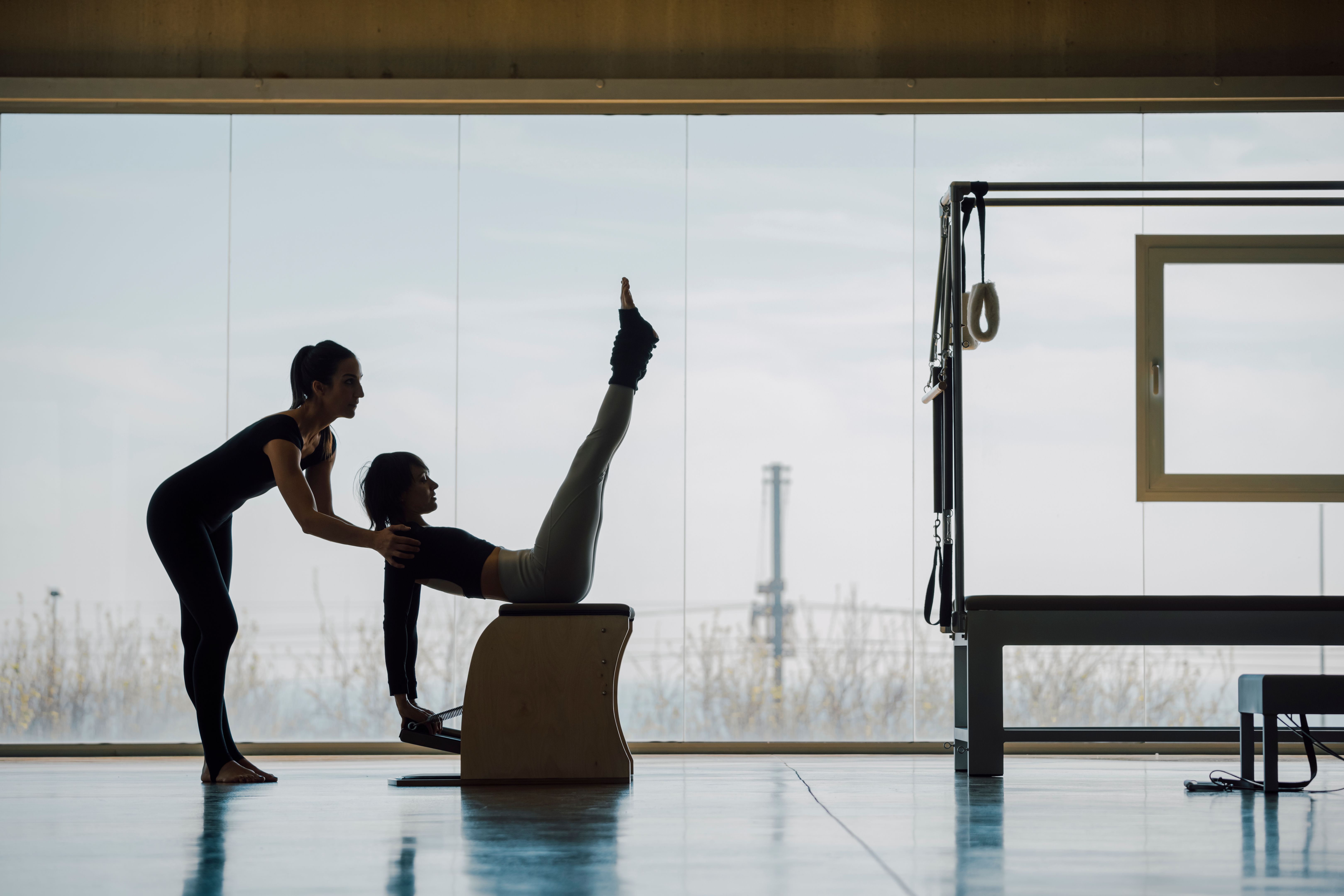 Pilates personal trainer working with his client in gym.