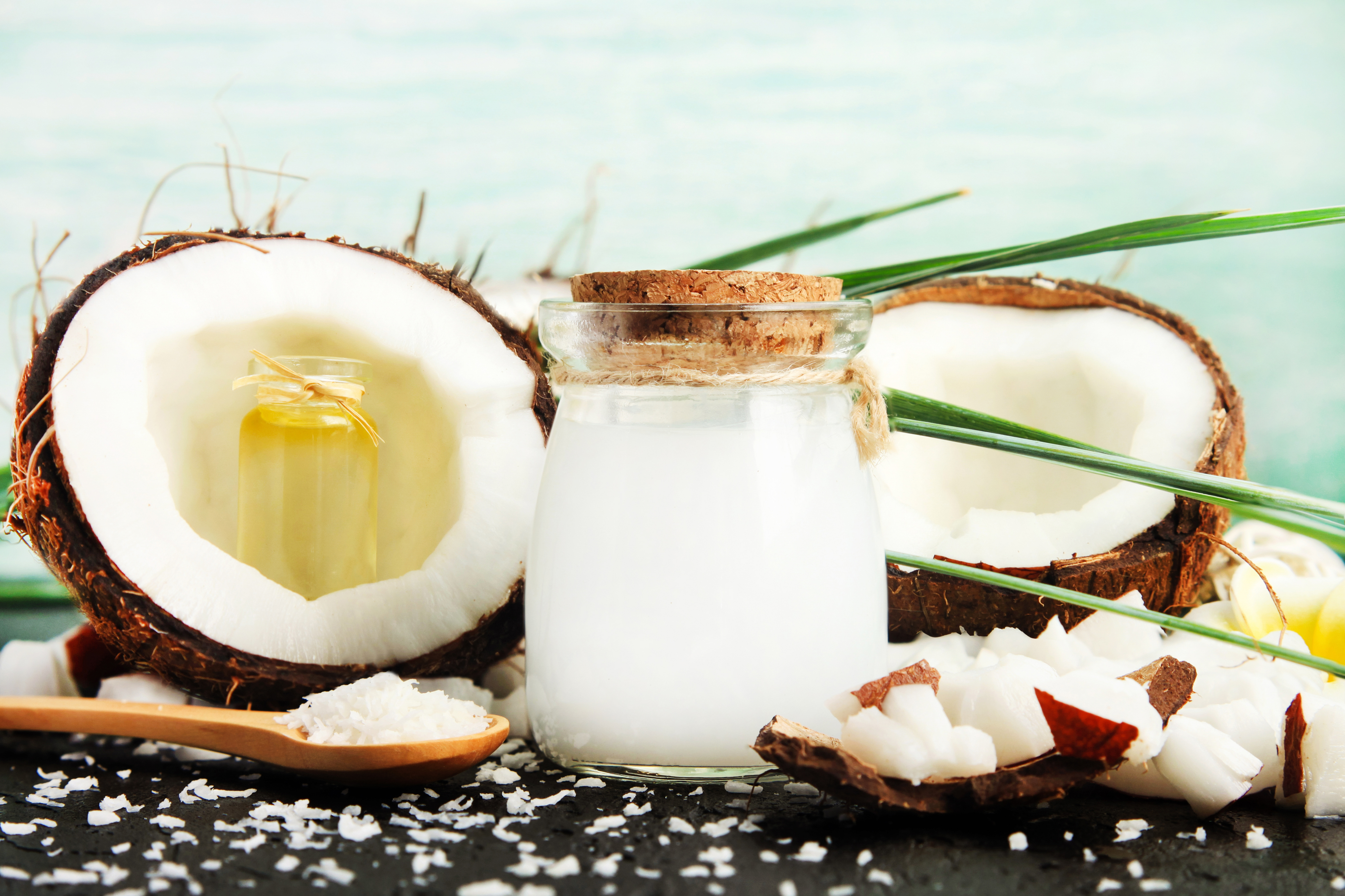 Coconut milk glass jar with nuts and oil bottles, fresh coconut flakes.