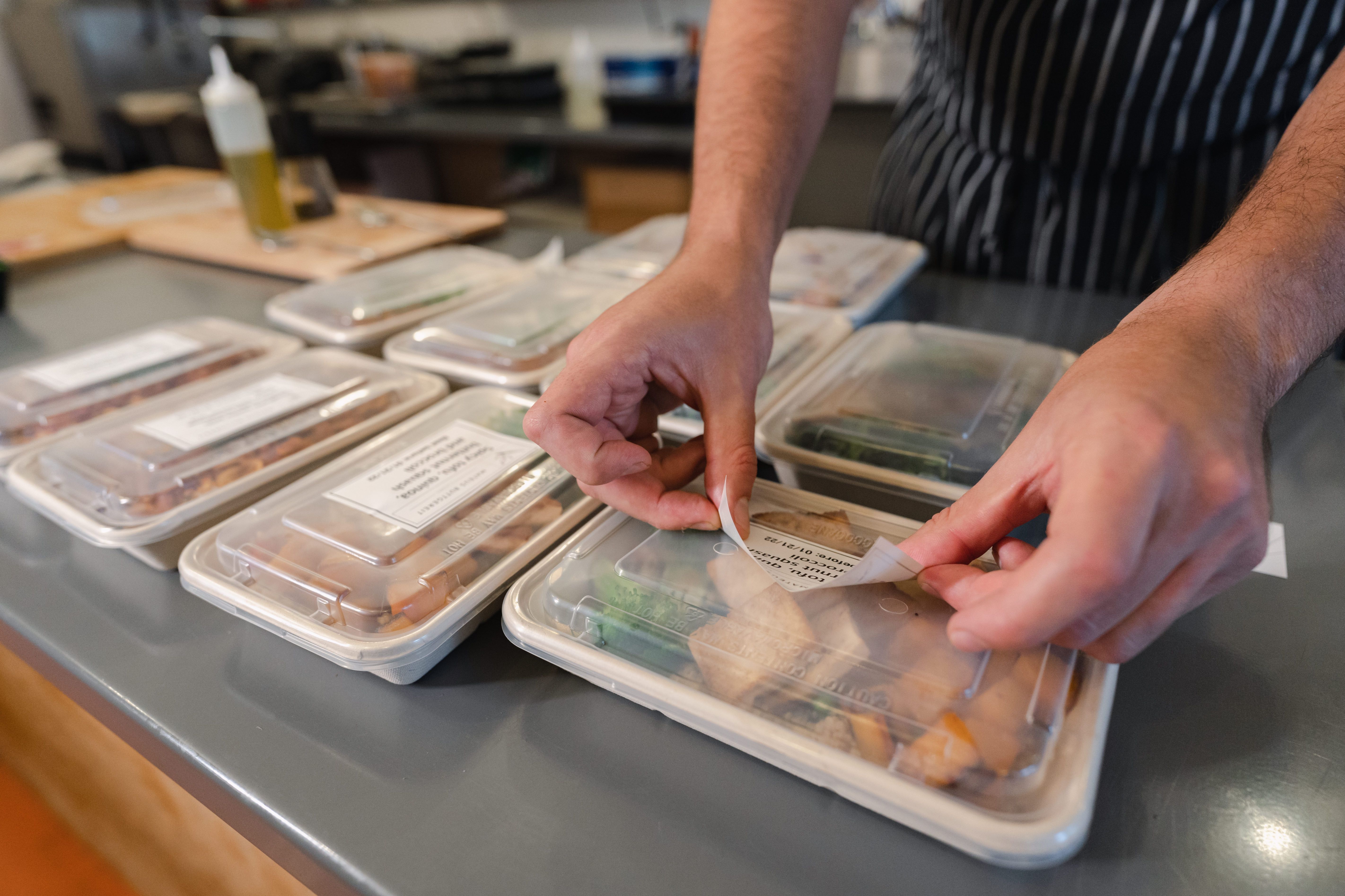 Chef cpackaging healthy food for delivery in eco friendly compostable trays and containers
