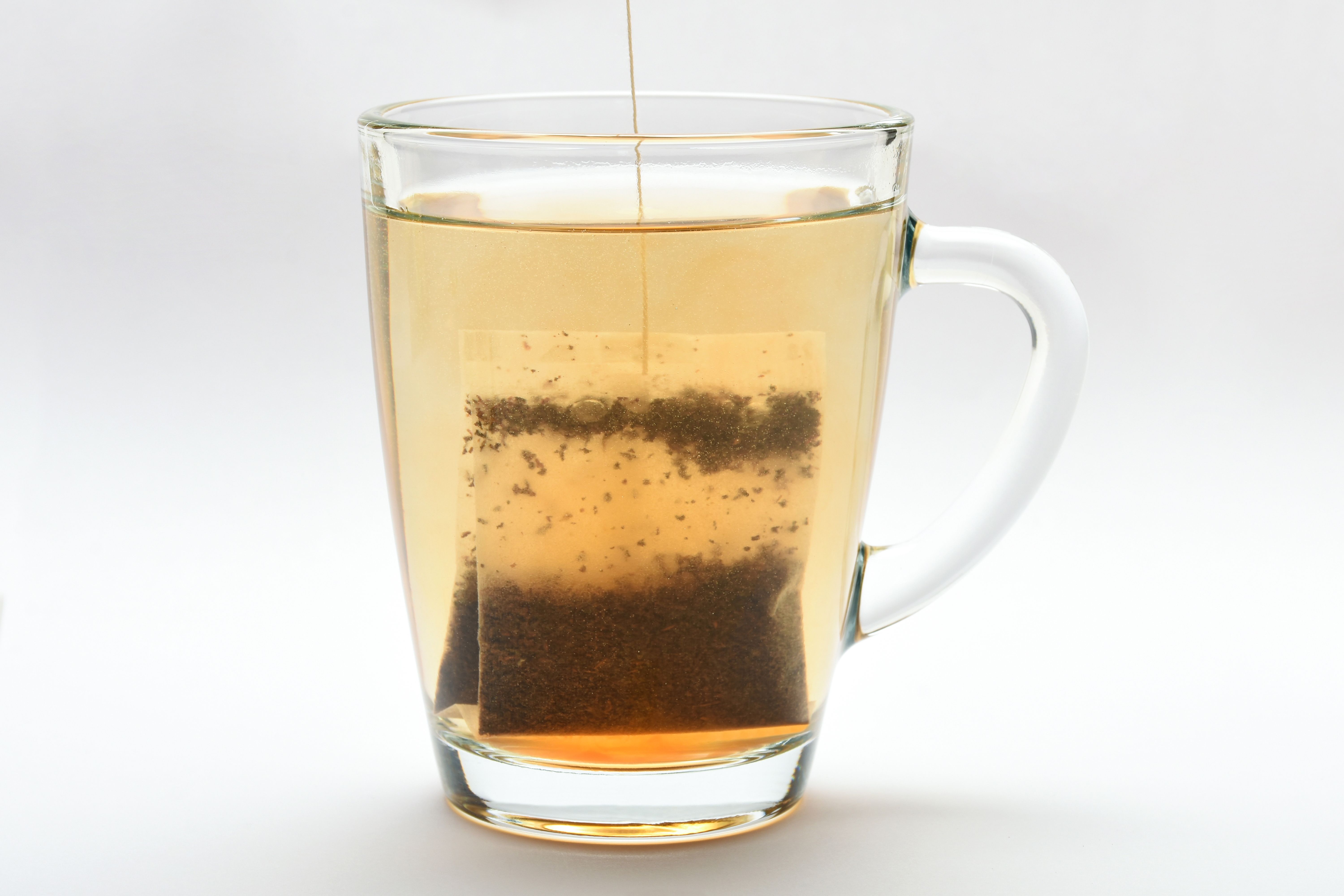 Teabag in heat water. Tea bag in a transparent tea cup on the white background
