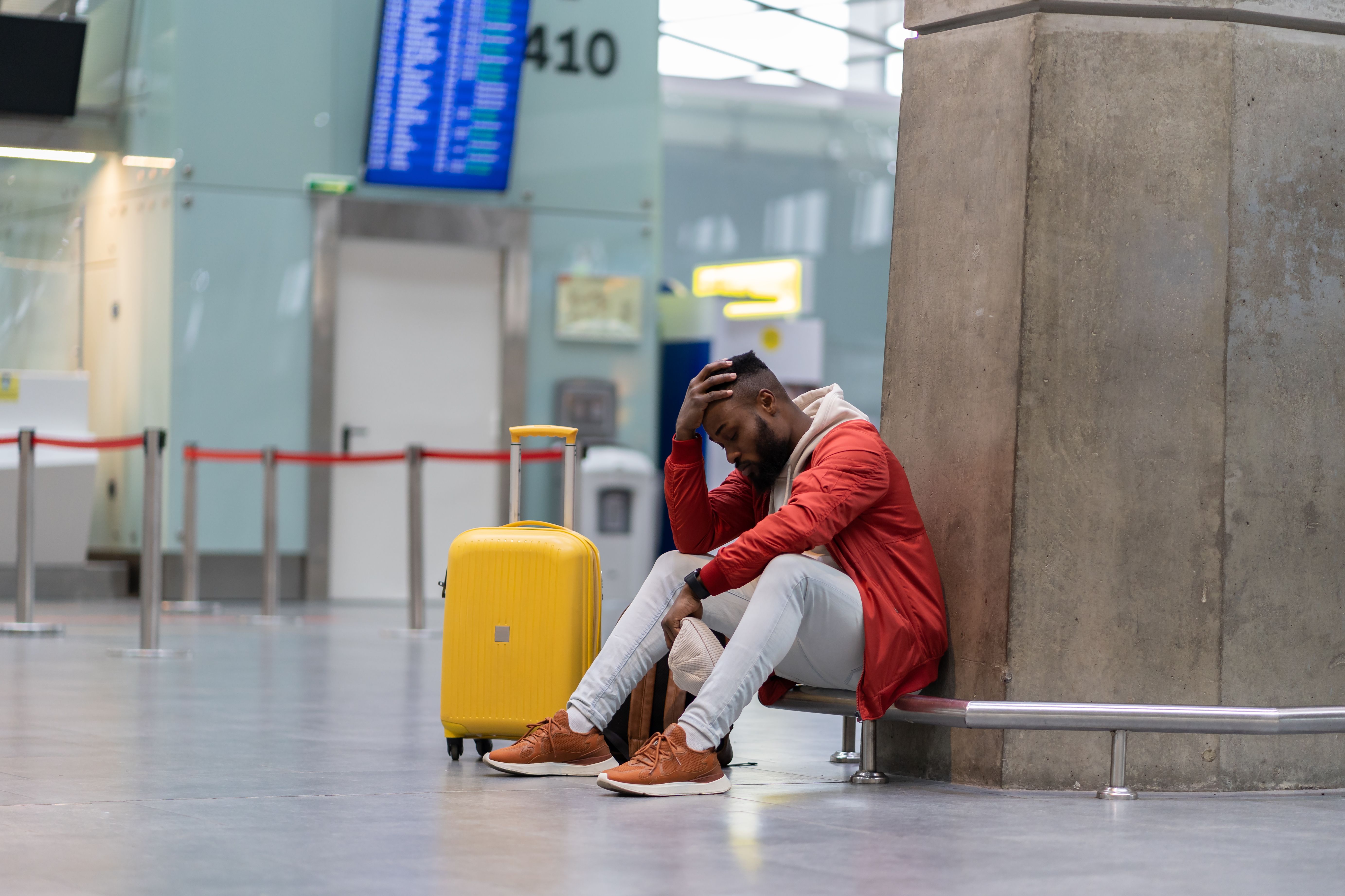 Exhausted African man on a long night connection at airport, waiting for a plane sitting in terminal
