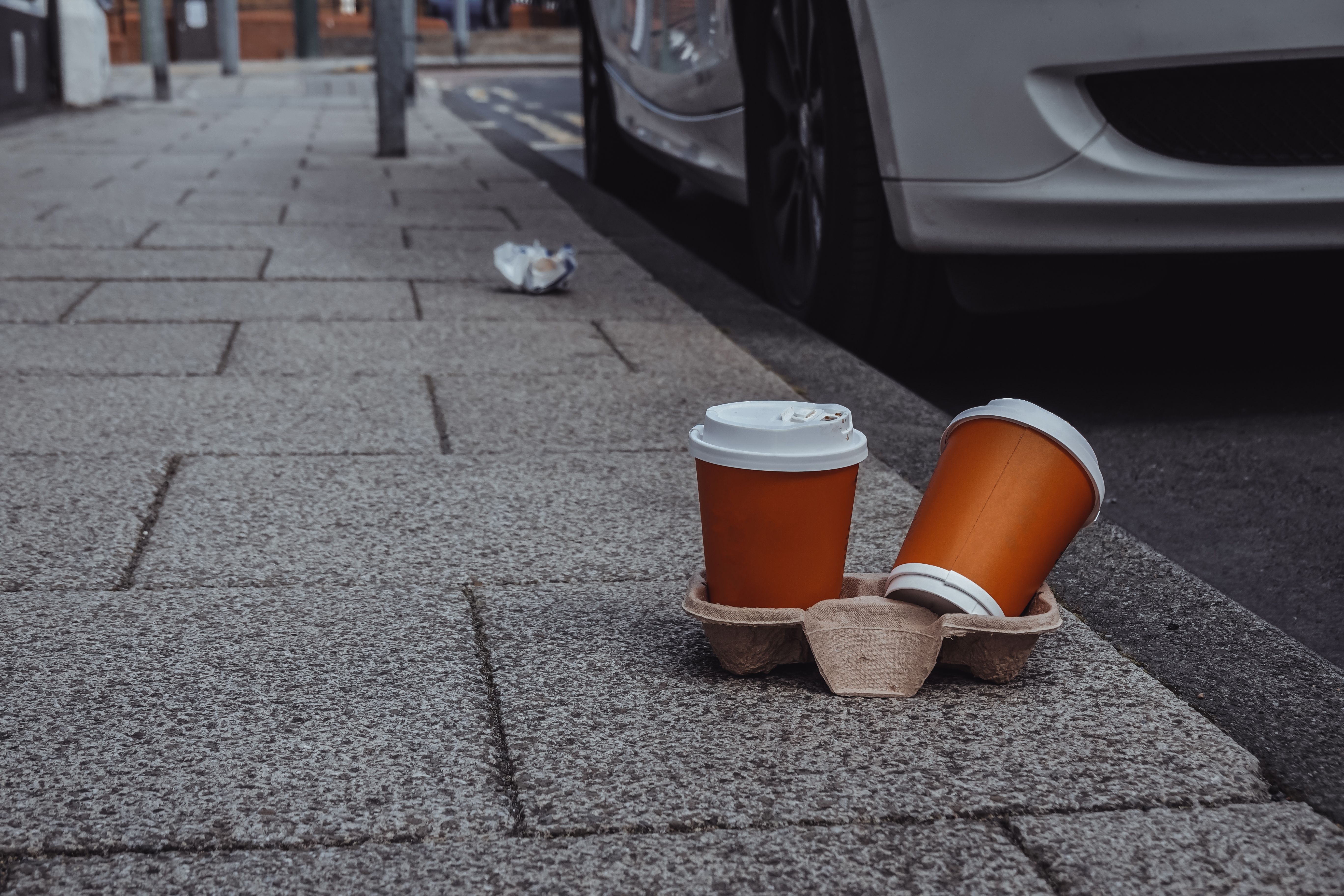 used  plastic cups left in the street, unclean street background, litter in the street