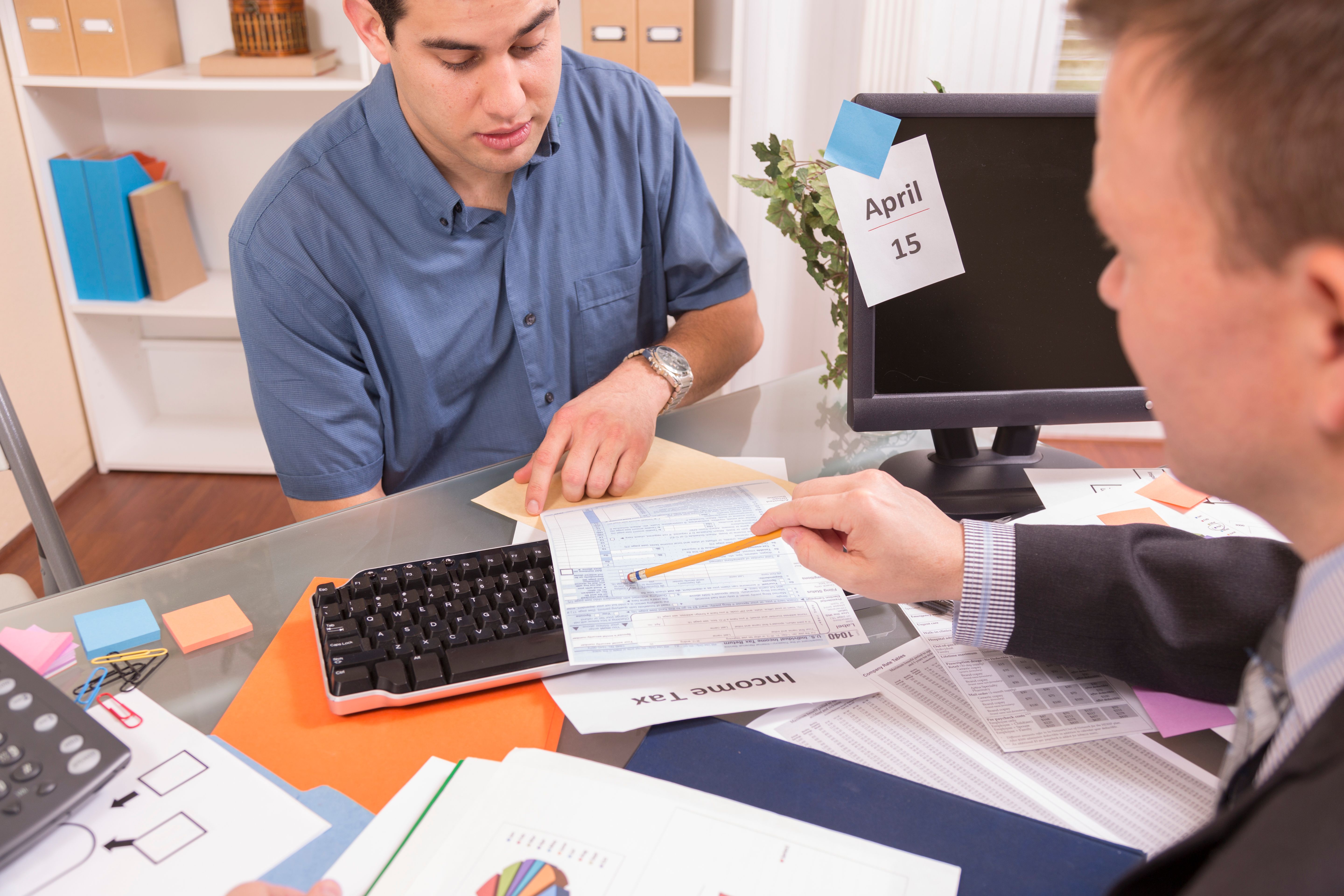 Business: Latin man reviews income tax documents with accountant.