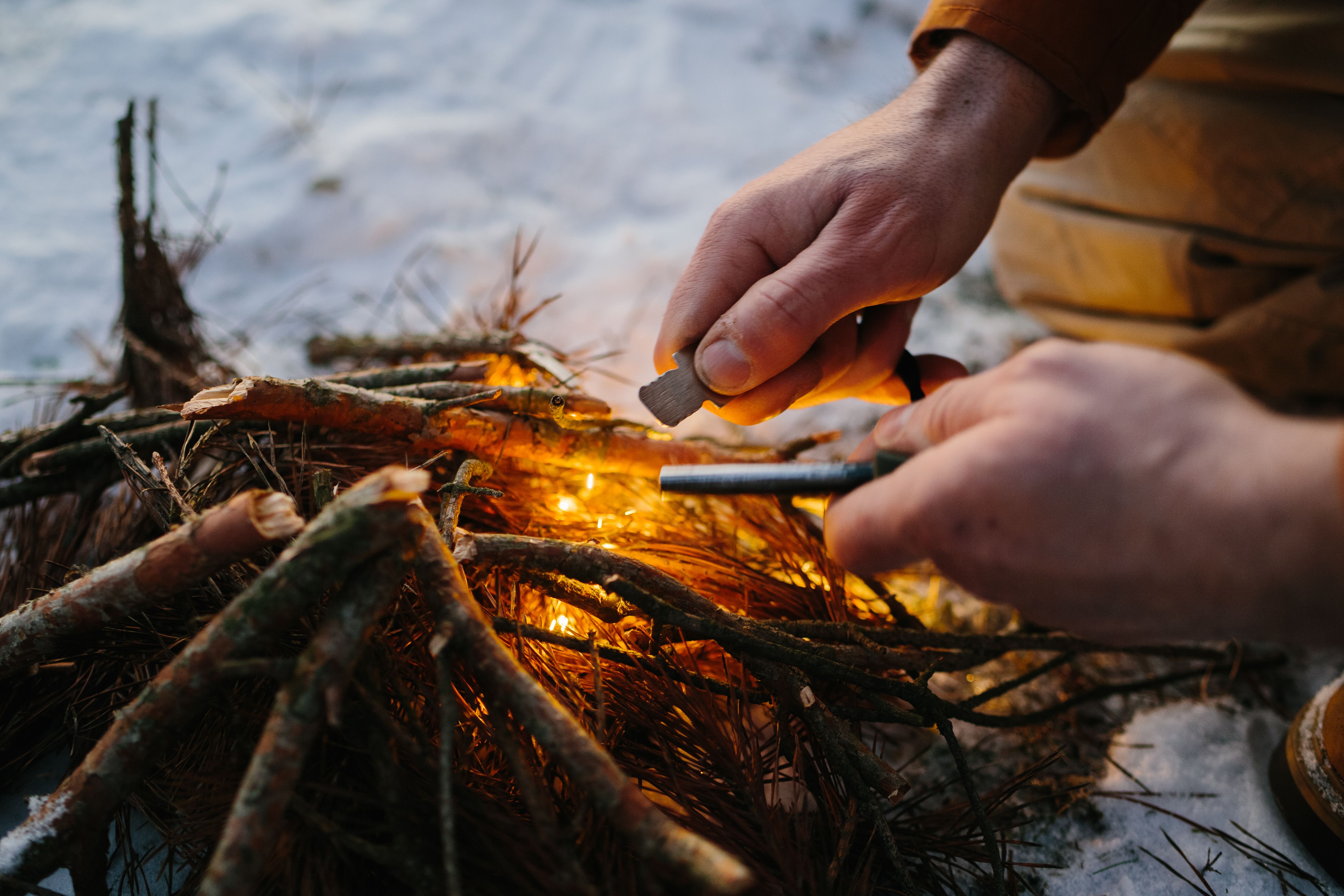 Closeup of male hand starts fire with magnesium fire steel, fire striker. Survival concept Closeup of male hand starts fire with magnesium fire steel, fire striker. Survival concept