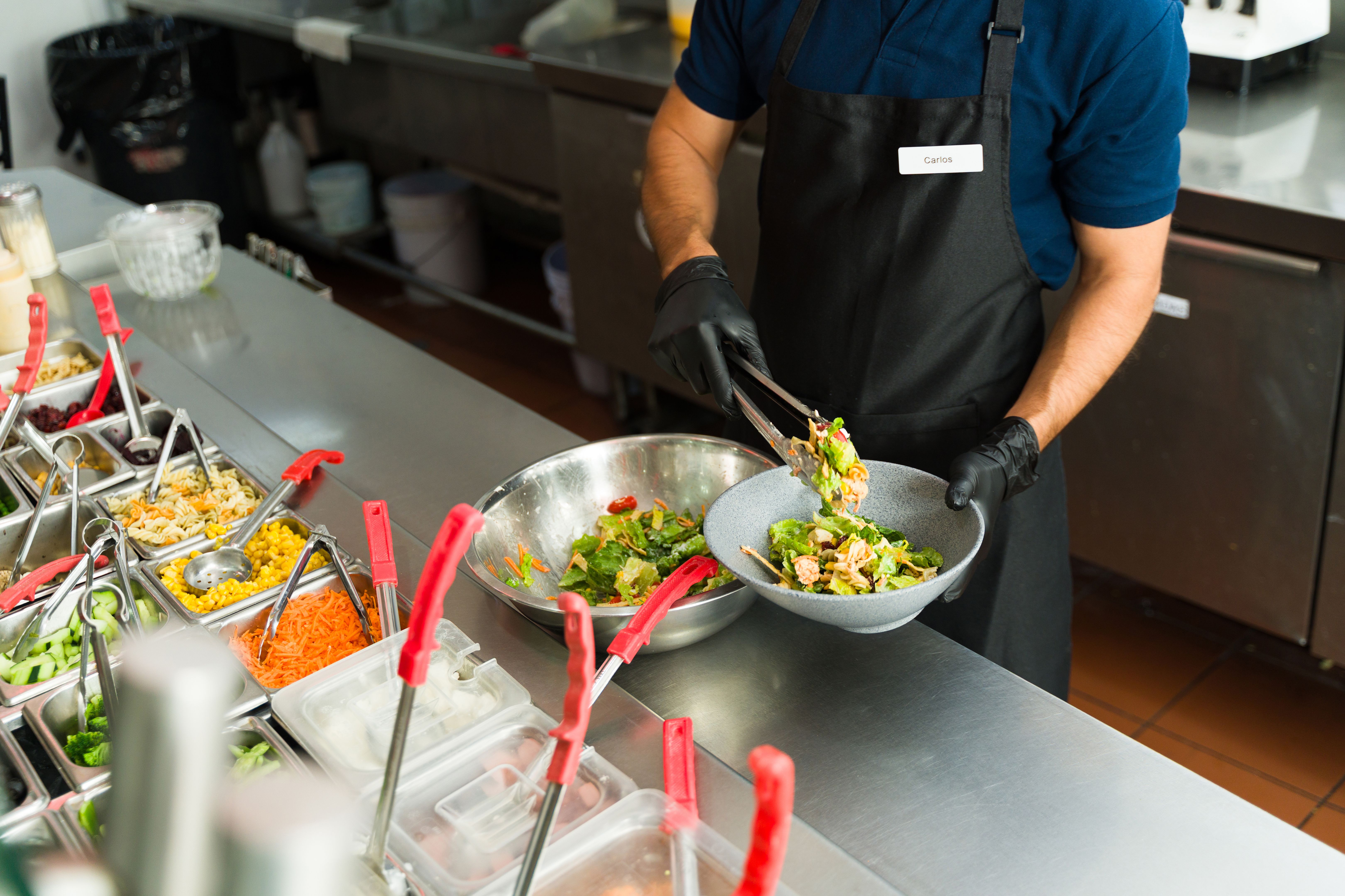 Cook preparing a fresh salad at salad bar restaurant